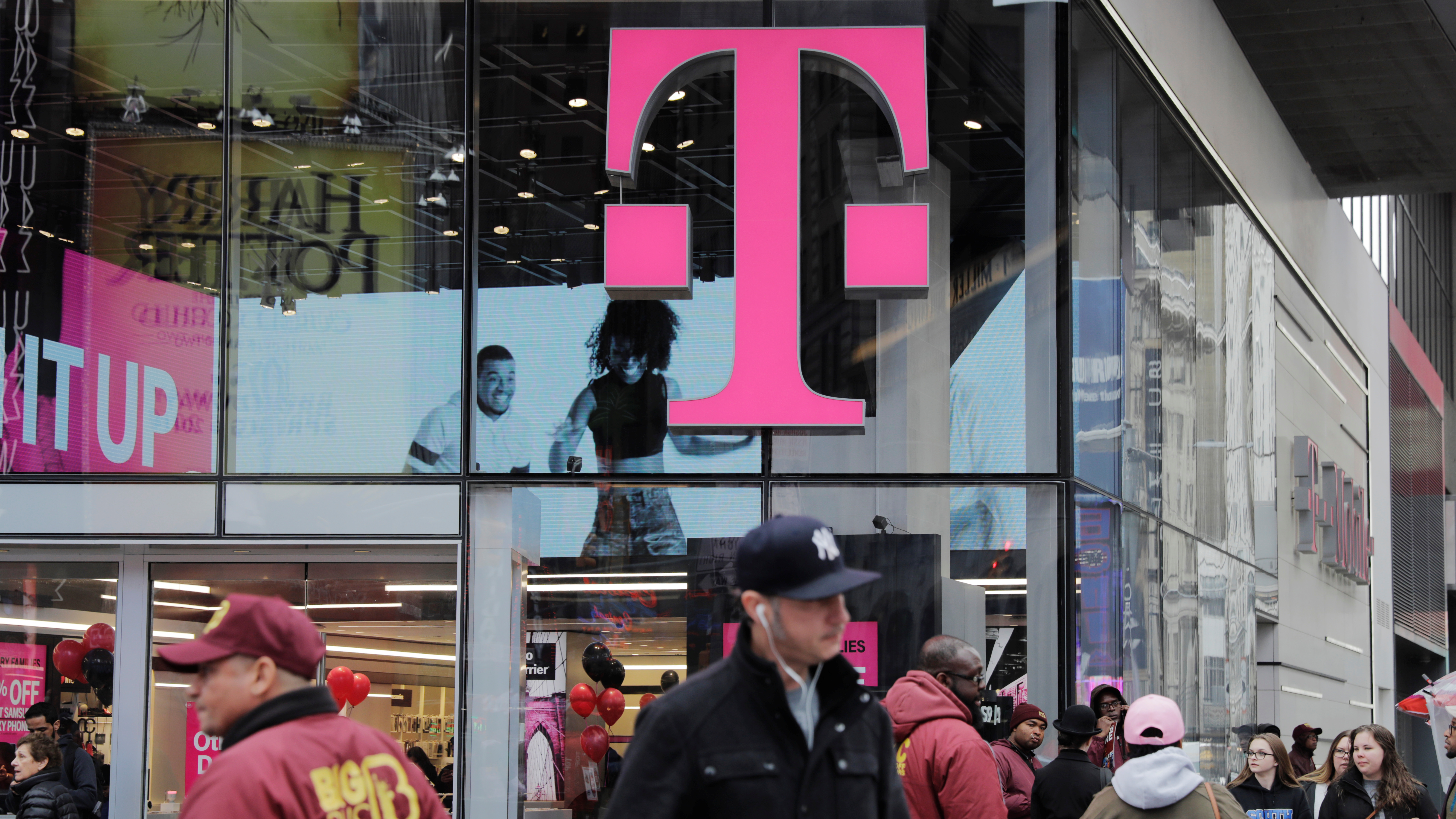 Pedestrians walk past a T-Mobile store in New York City on Friday. Sprint and T-Mobile are seeking to merge, but the proposed deal sill requires regulatory approval.