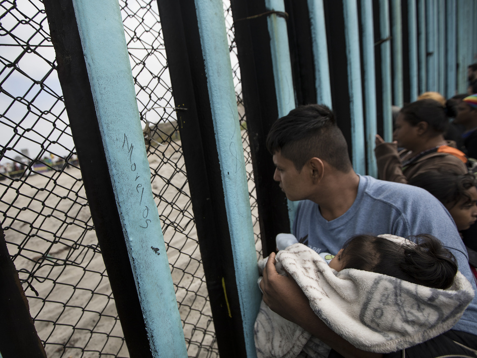 Central American migrants look through the border wall near the ocean in Tijuana, Mexico, in April. (Hans-Maximo Musielik/AP)