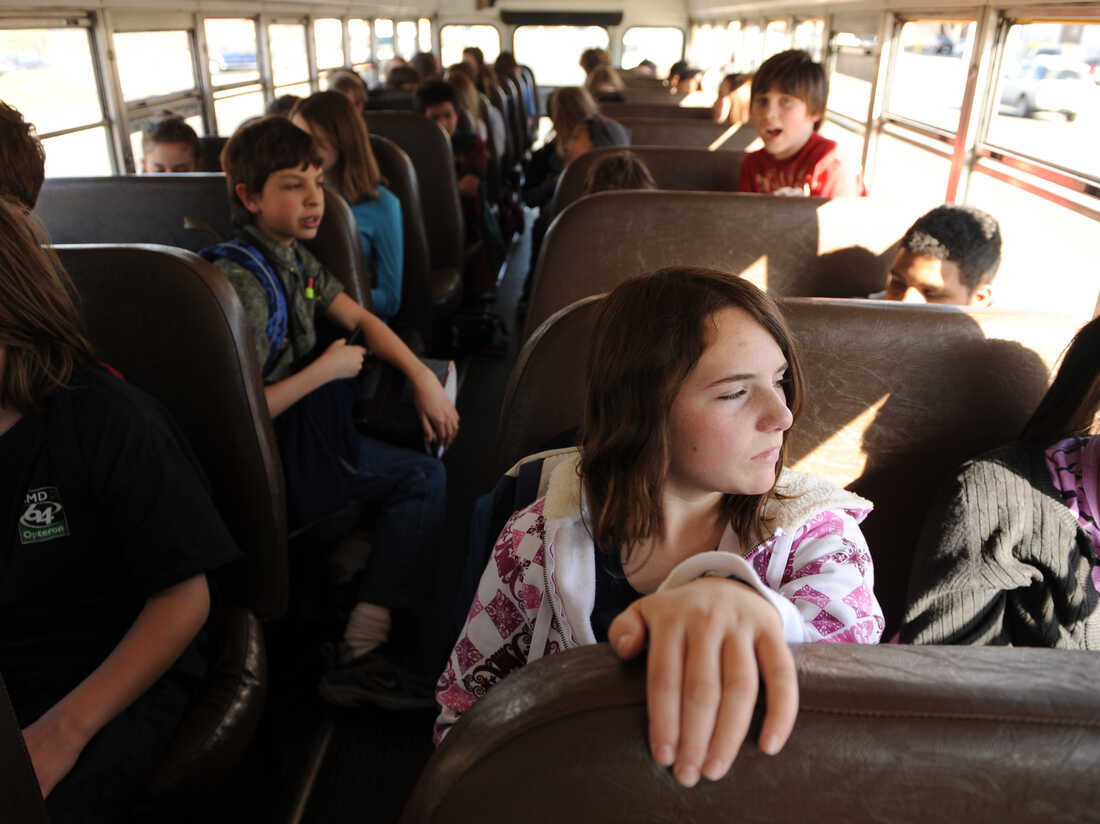 Kids slog to school on a bus.