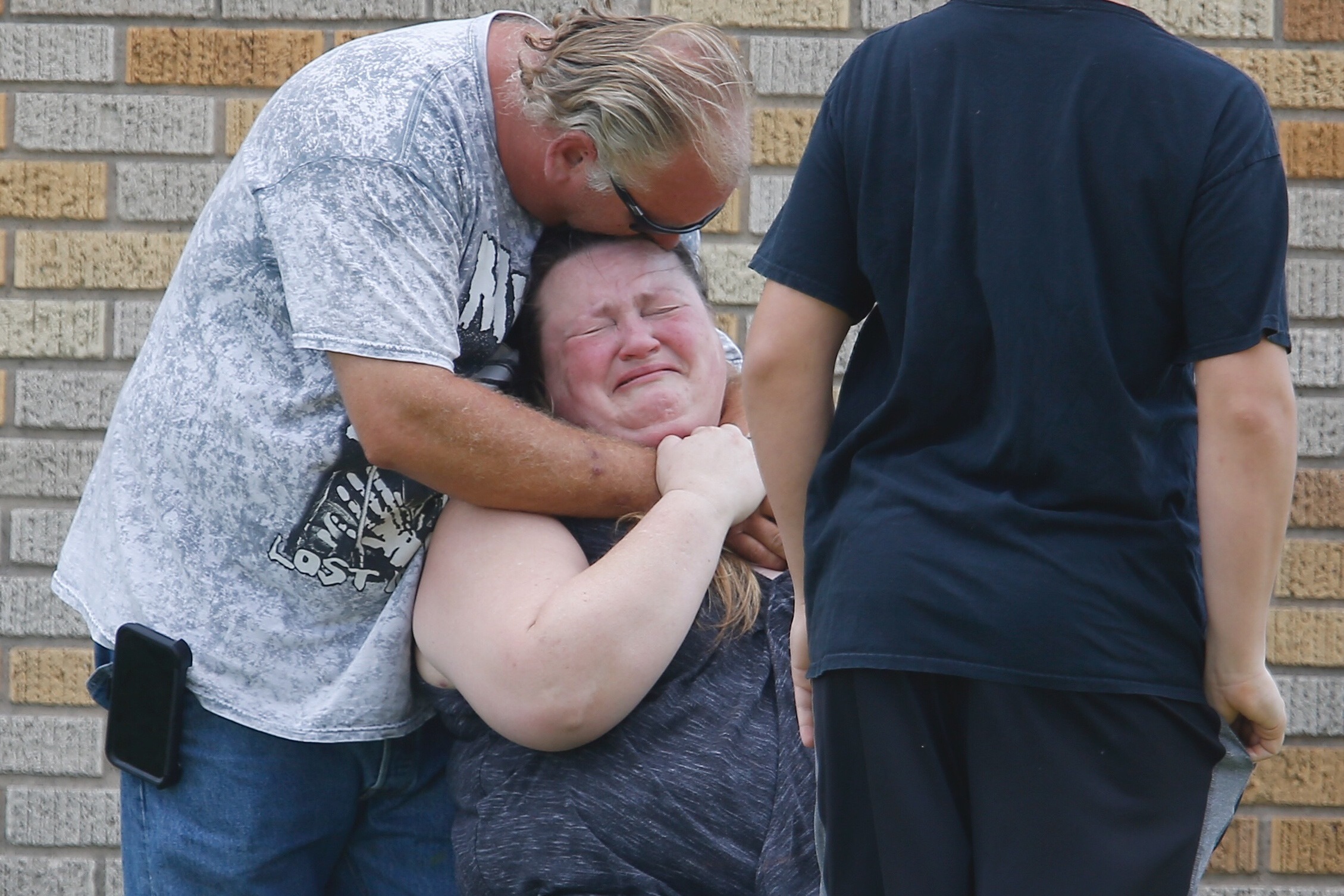 A man hugs a woman outside the Alamo Gym where parents wait to reunite with their kids following a shooting at Santa Fe High School. (Houston Chronicle)