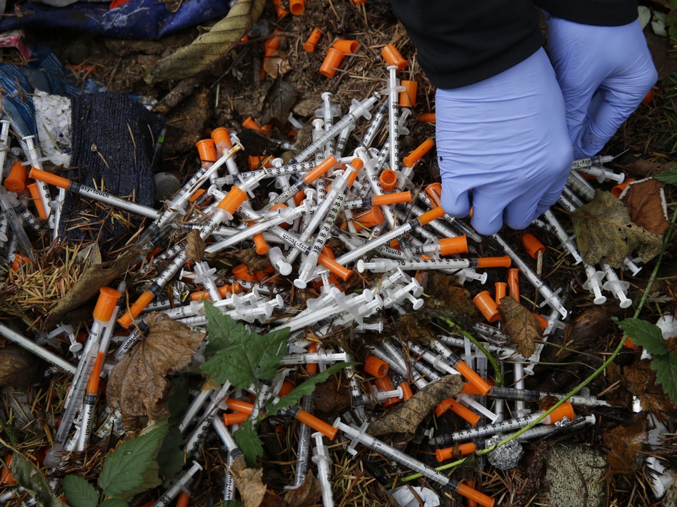 A volunteer cleans up needles used for drug injection that were found at a homeless encampment in Everett, Wash., in November. Respondents in a Federal Reserve survey who knew someone who had been addicted to opioids were less likely to give the economy a favorable rating. (Ted S. Warren/AP)