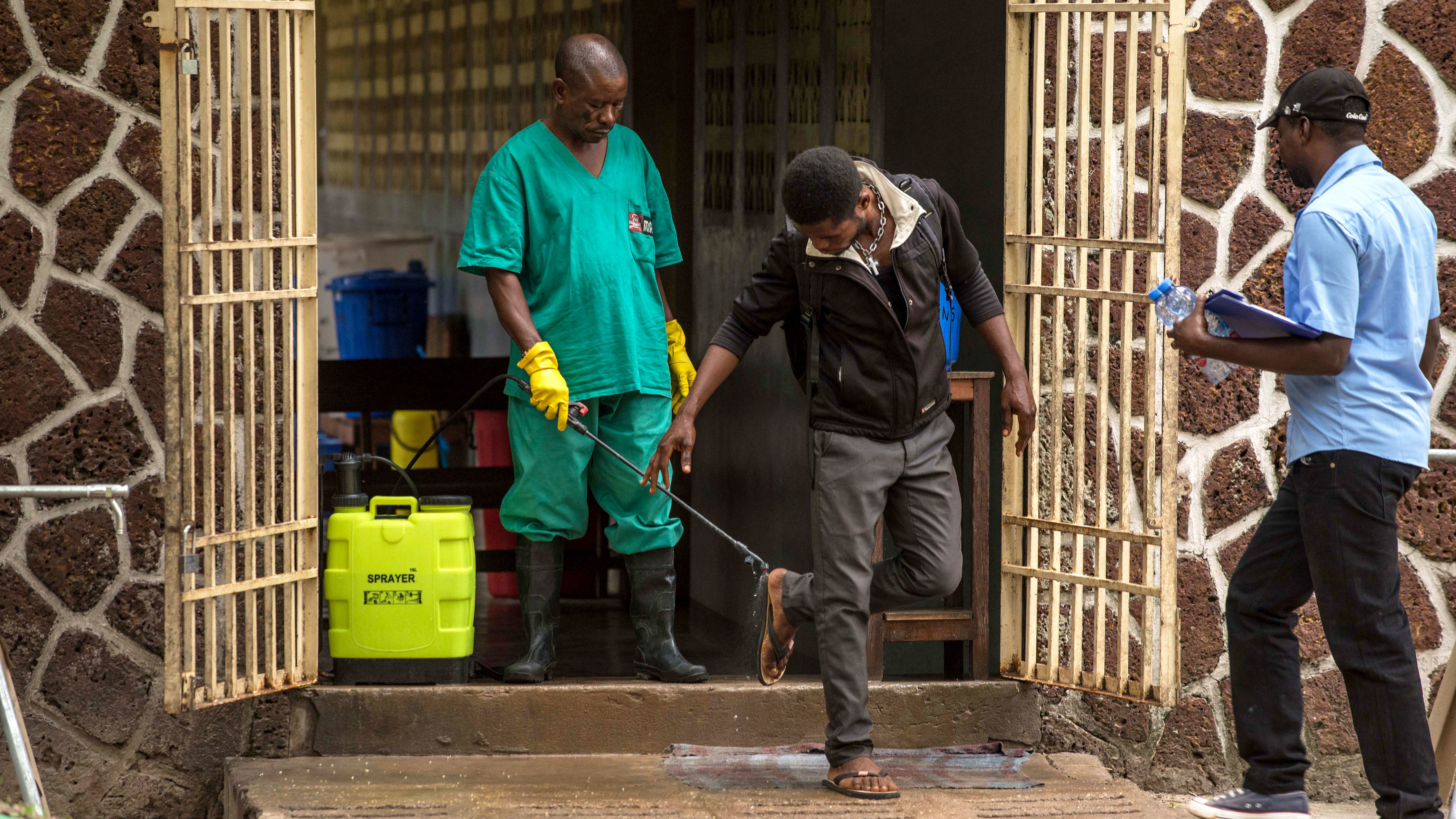 A worker disinfects shoes outside the Ebola security zone at a hospital in Mbandaka in the Democratic Republic of the Congo.
