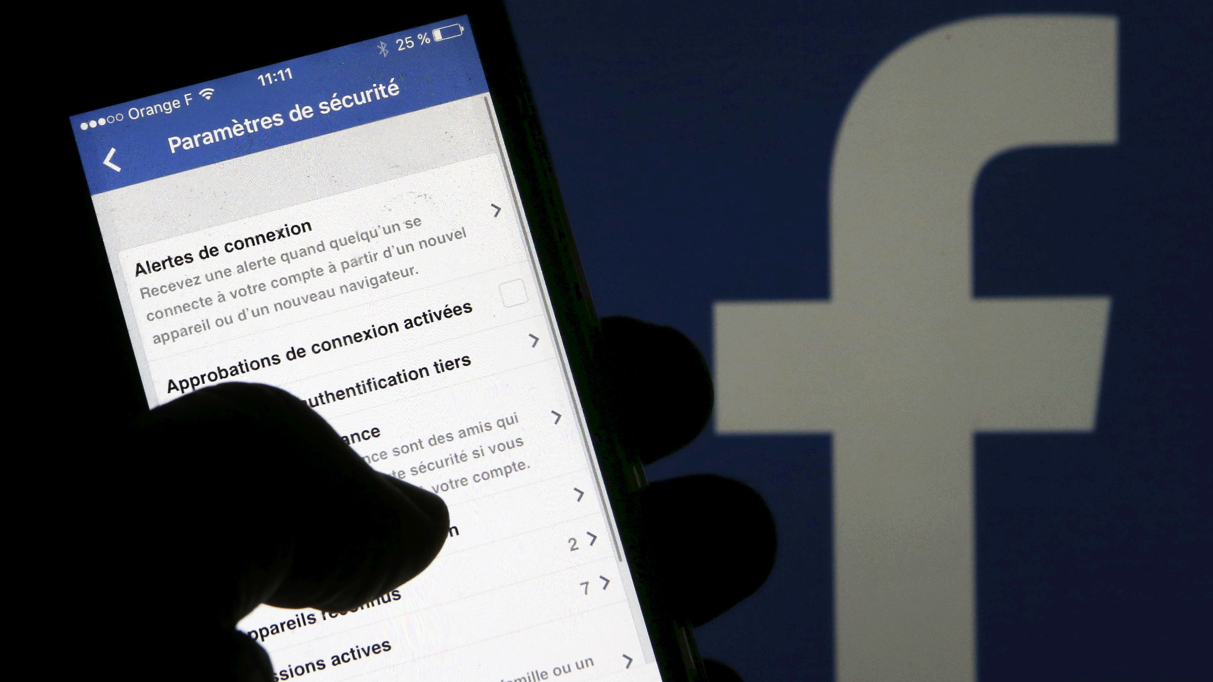 Facebook says it disagrees with how <em>The New York Times</em> is presenting data-sharing deals it has used for at least 10 years. Here, a man reads security parameters on his phone in front of a Facebook logo in Bordeaux, southwestern France. (Reuters)