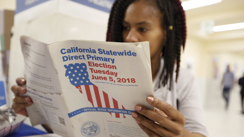 Nikko Johnson reviews the California Primary election guide at San Francisco City Hall on Tuesday. (Lorin Eleni Gill/AP)