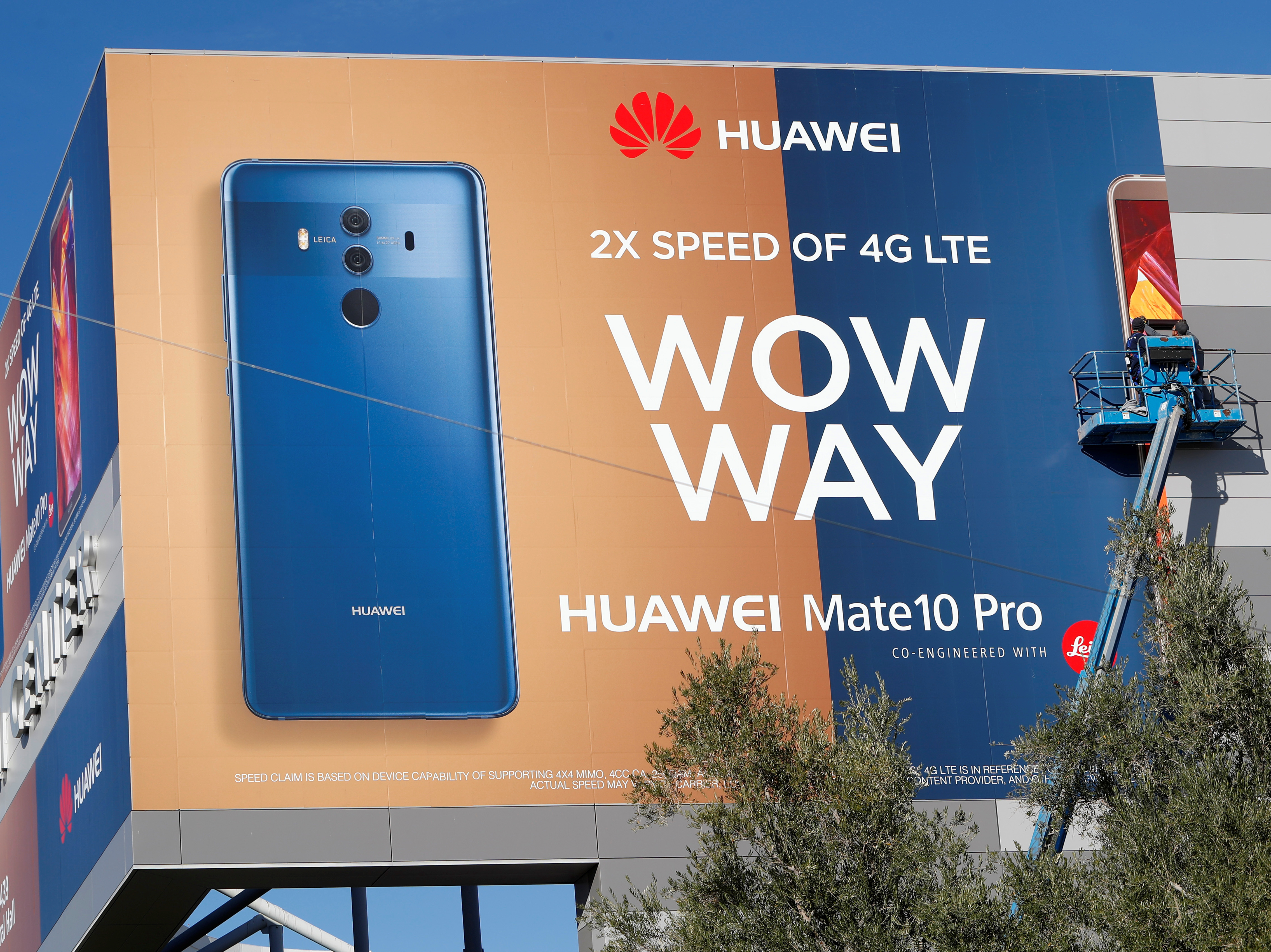 A crew hangs a Huawei advertising banner on the side of the Las Vegas Convention Center in January. Some senators want to ban it the world's third-largest seller of smartphones from the U.S. (Reuters)