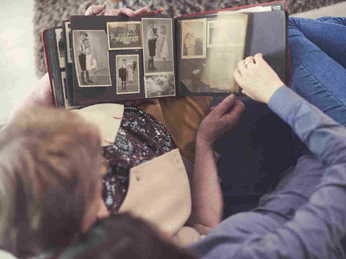 Two people look at a photo album of old photos.