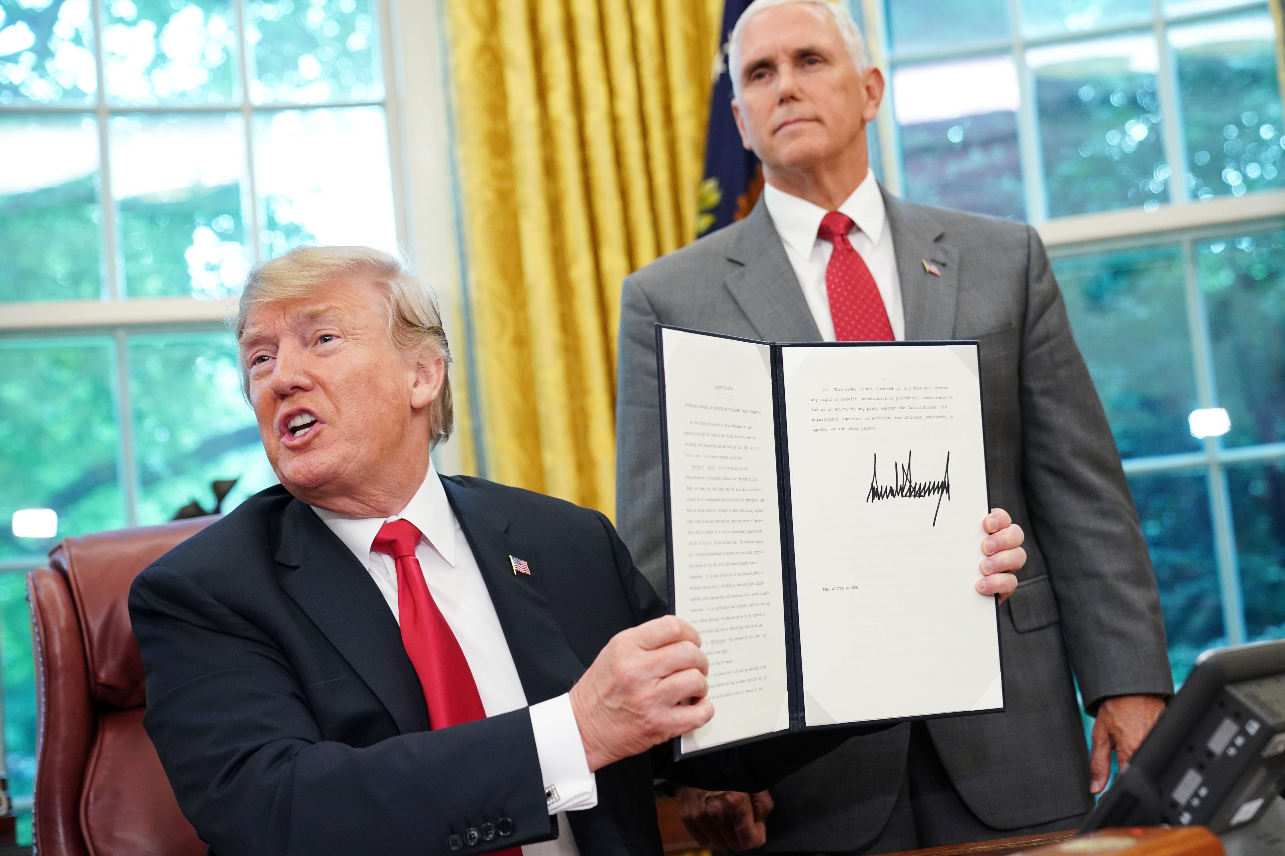 Watched by Vice President Pence, President Trump on Wednesday shows an executive order on immigration aimed at putting an end to the controversial separation of migrant families at the border. (Mandel Ngan/AFP/Getty Images)