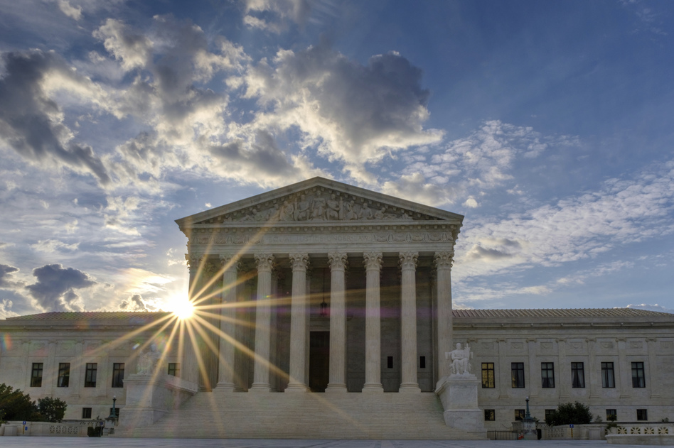 The sun flares in the camera lens as it rises behind the U.S. Supreme Court building in Washington. (J. David Ake/AP)