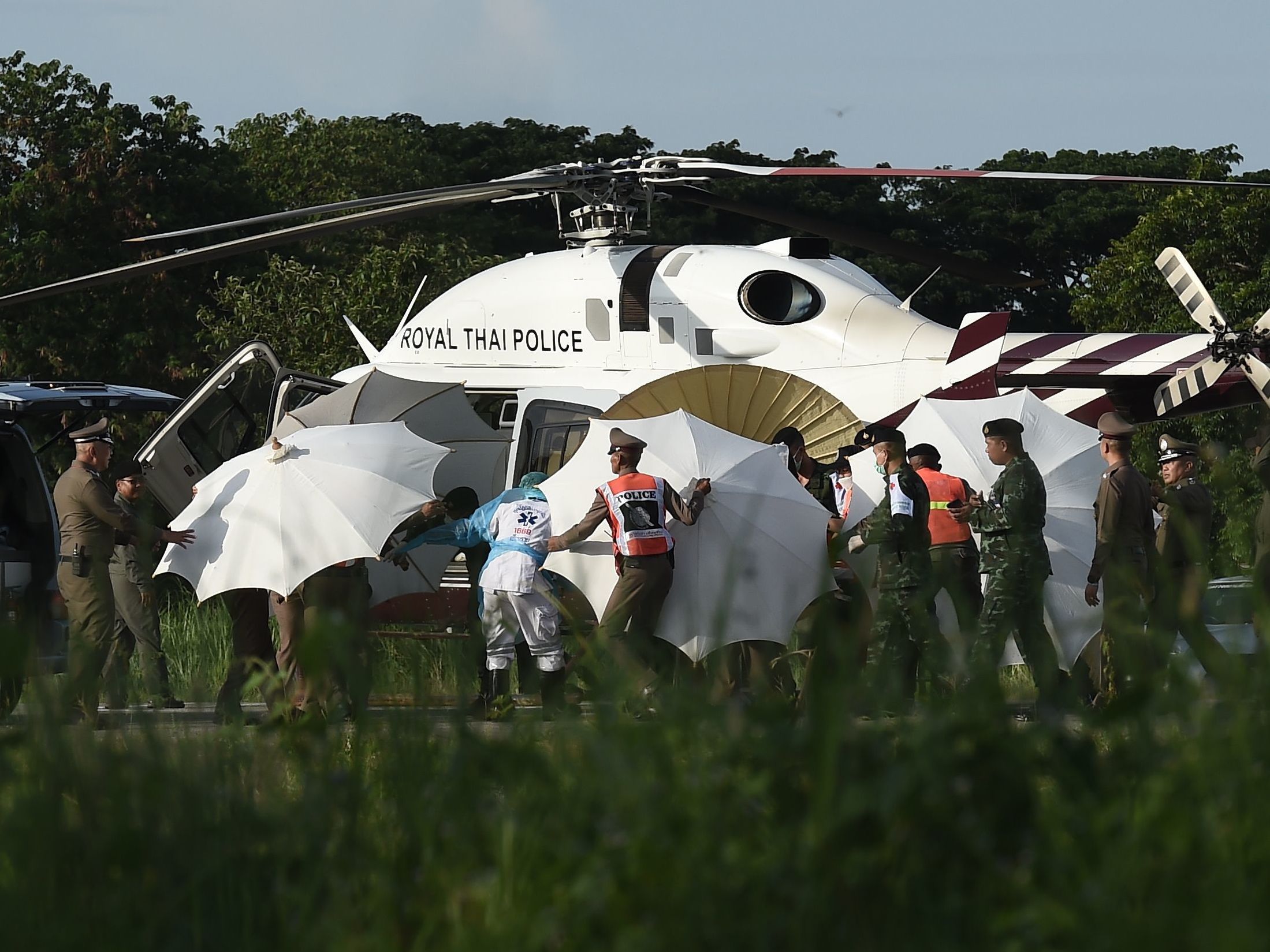 Police and military personnel use umbrellas to cover a stretcher as it is carried to a helicopter from an ambulance at a military airport in Chiang Rai, Thailand, on Monday, as rescue operations continued for those still trapped inside the cave in Khun Nam Nang Non Forest Park in the Mae Sai district. (AFP/Getty Images)