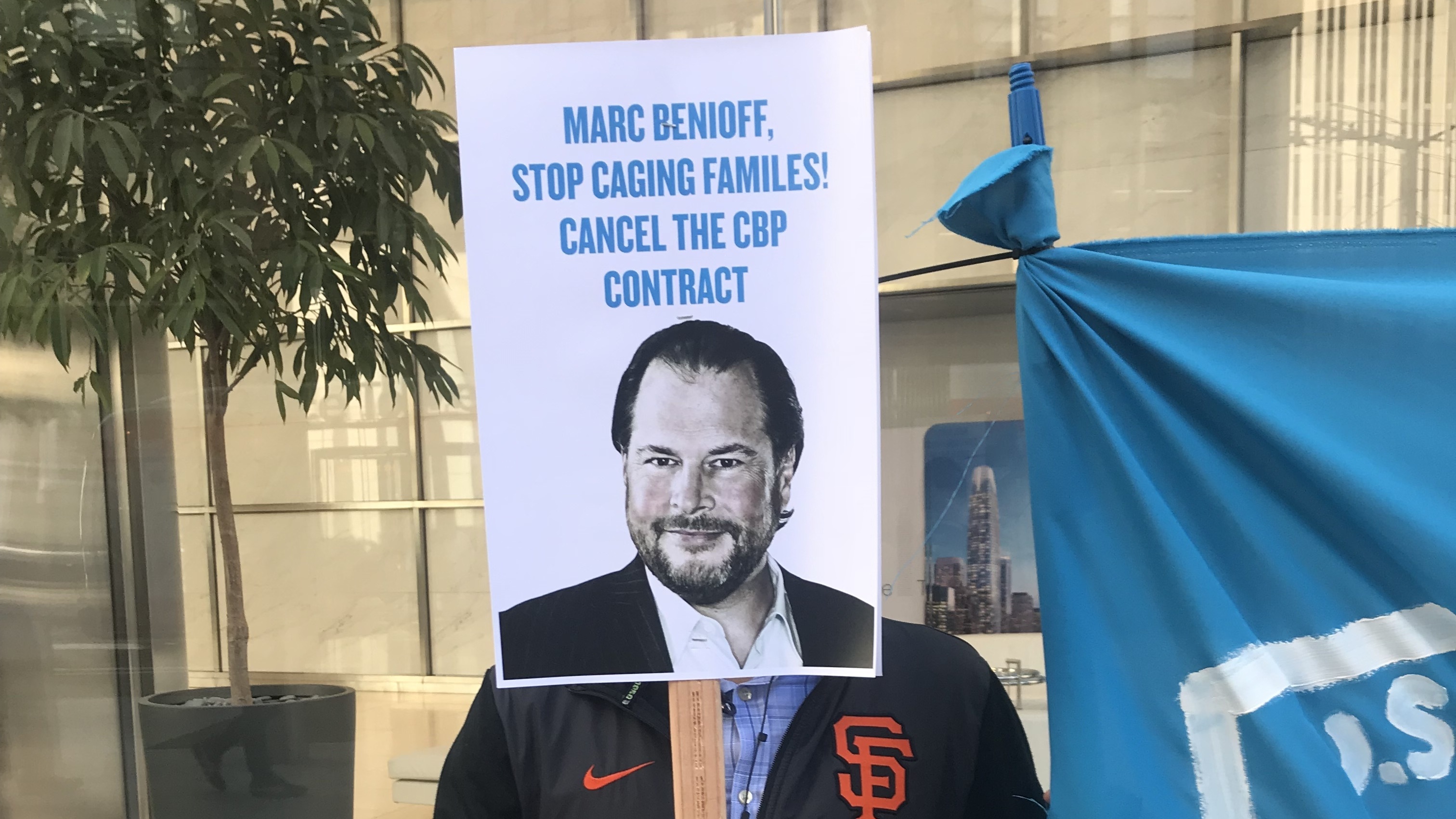 A protester holds up a sign targeting Salesforce CEO Marc Benioff outside the company