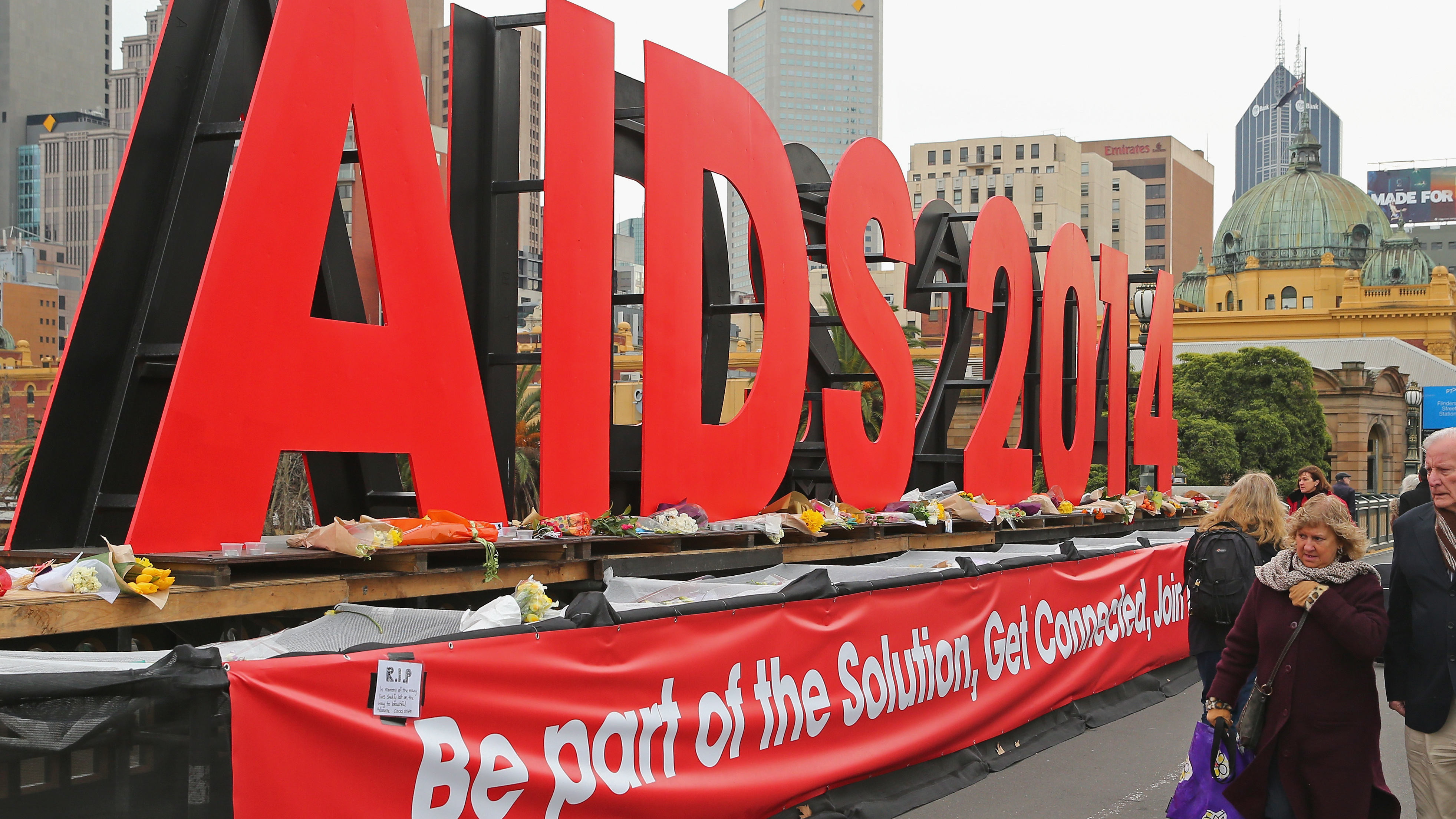 People walk past tributes to the victims of MH17, placed on signage for the 20th International AIDS Conference in Australia in 2014. Several AIDS activists on their way to the conference were killed.