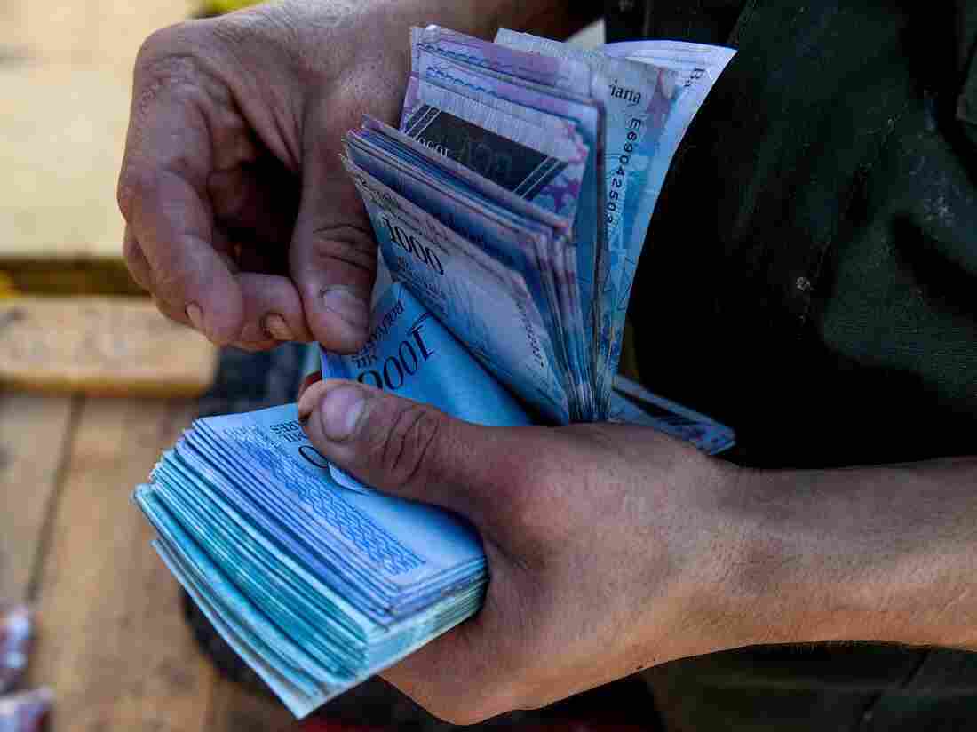 A man counts 1000-Bolivar-bills to buy groceries at the municipal market of Coche, a neighbourhood of Caracas, on June 20, 2018.