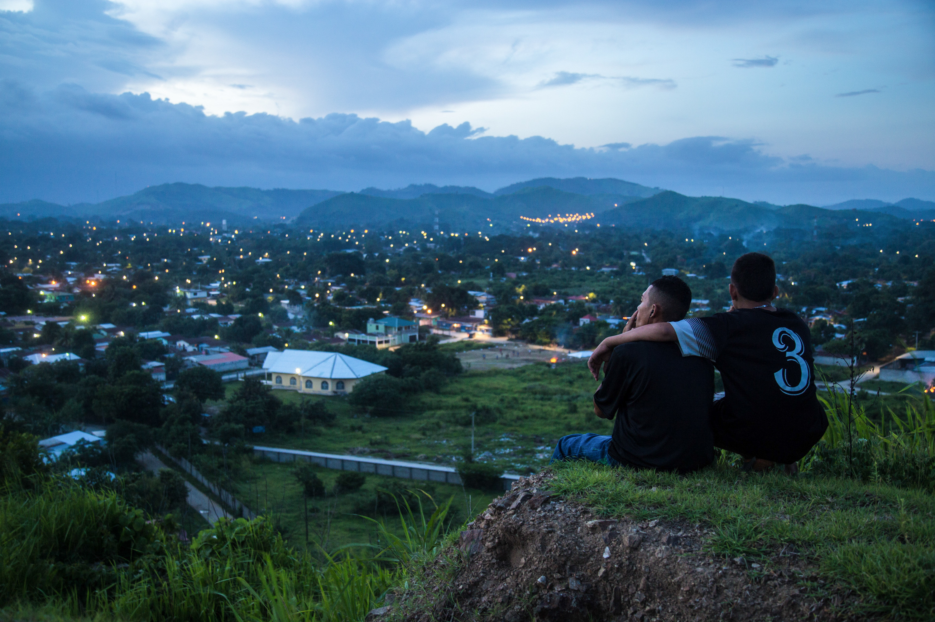 Moises, 17, left, and Jaime look down on the patchwork of neighborhoods outside San Pedro Sula, a city in Honduras where gang rivalries play out. The violence is so bad that &quot;no one goes in&quot; the neighborhoods, says photojournalist Tomas Ayuso. &quot;Food delivery trucks, ambulances don't want to go in because they're afraid something will happen.&quot; (Tomas Ayuso)