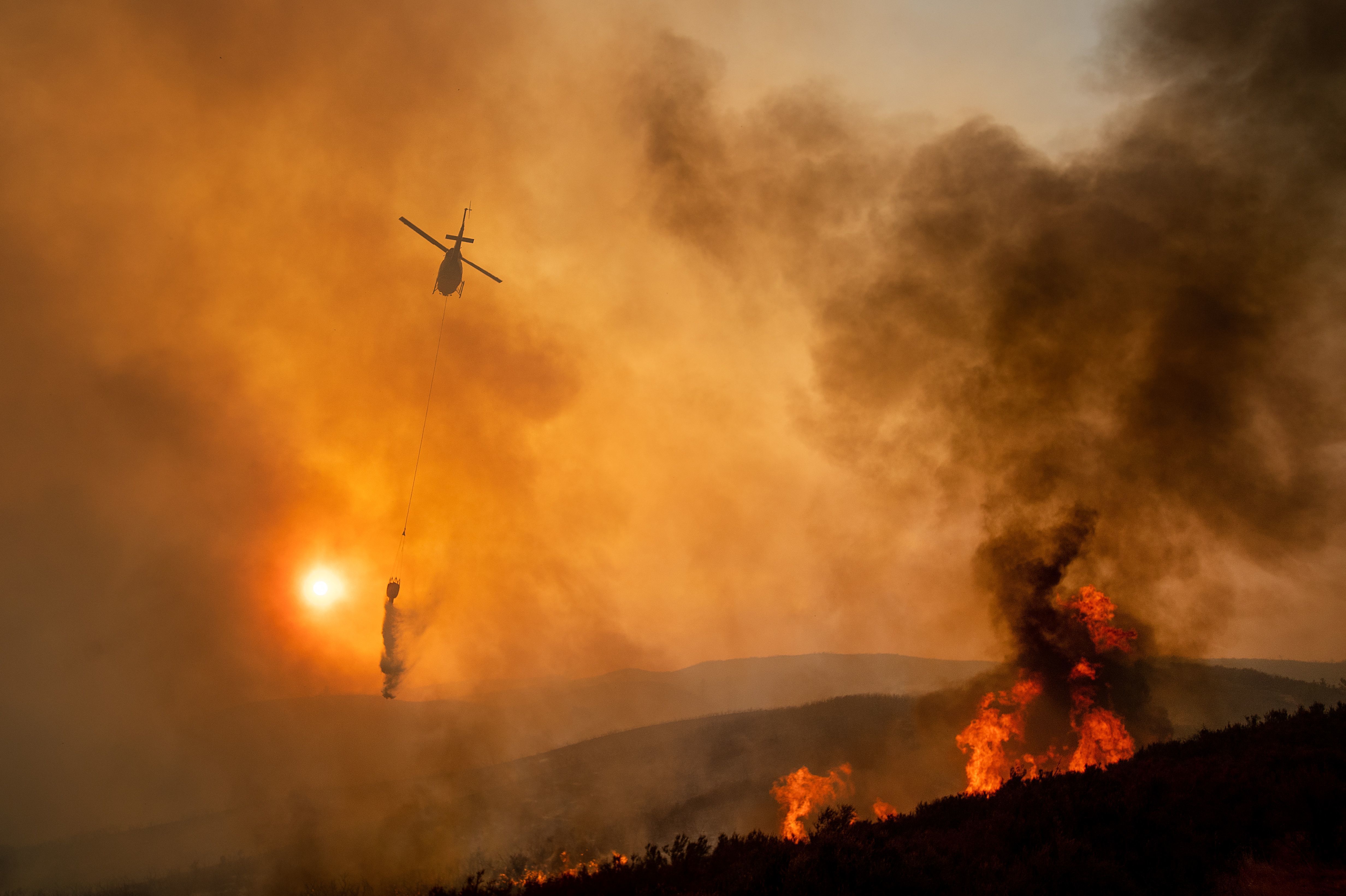 A helicopter drops water while battling the Ranch Fire, part of the Mendocino Complex Fire, near Clearlake Oaks, Calif., on Sunday. (AFP/Getty Images)