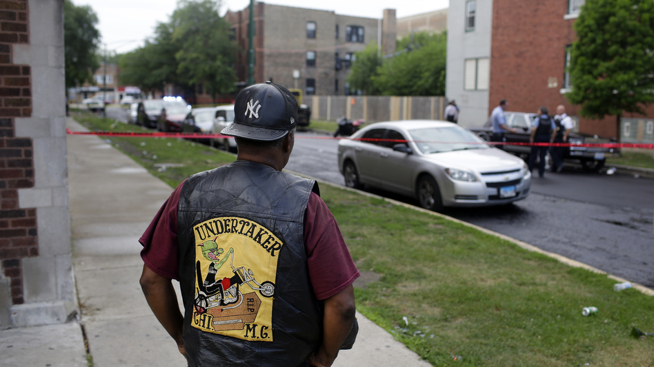 A bystander watches as Chicago police investigate a street where multiple people were shot on Sunday. (Joshua Lott/Getty Images)