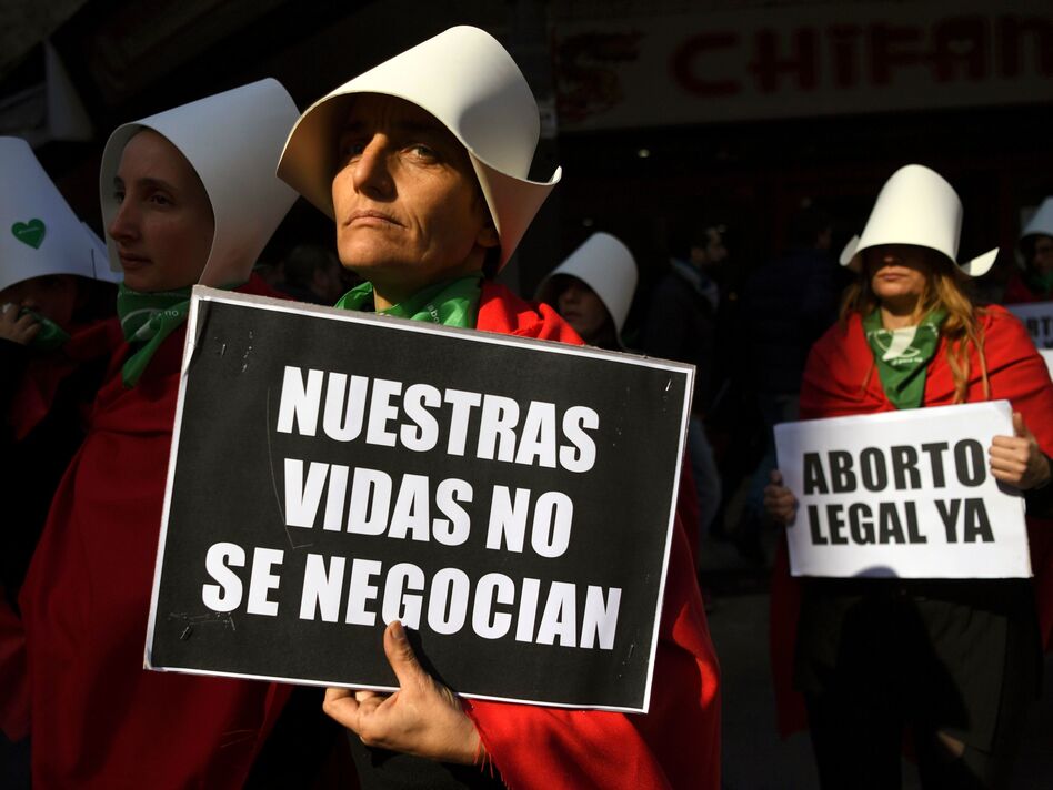 Abortion-rights supporters demonstrate earlier this month outside the National Congress in Buenos Aires, adding the legalization campaign's distinctive green handkerchiefs to outfits alluding to the dystopian novel <em>The Handmaid's Tale</em>. The book's author, Margaret Atwood, has said she drew inspiration from Argentine history. (Eitan Abramovich/AFP/Getty Images)