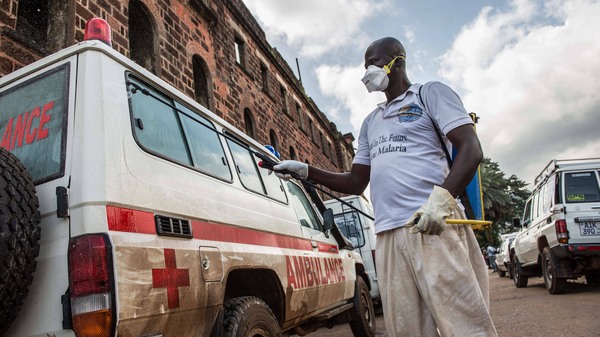 At the main ambulance base in central Freetown, Sierra Leone, a government health worker disinfects ambulances with chlorine spray during the 2014 Ebola outbreak.