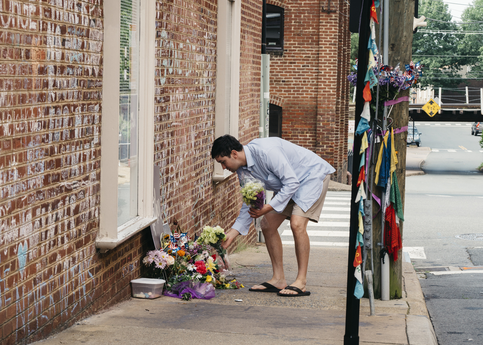 Peter Reijmers, 29, of Charlottesville, lays flowers at a memorial on 4th Street SE where Heather Heyer was killed last August. (Justin T. Gellerson for NPR)