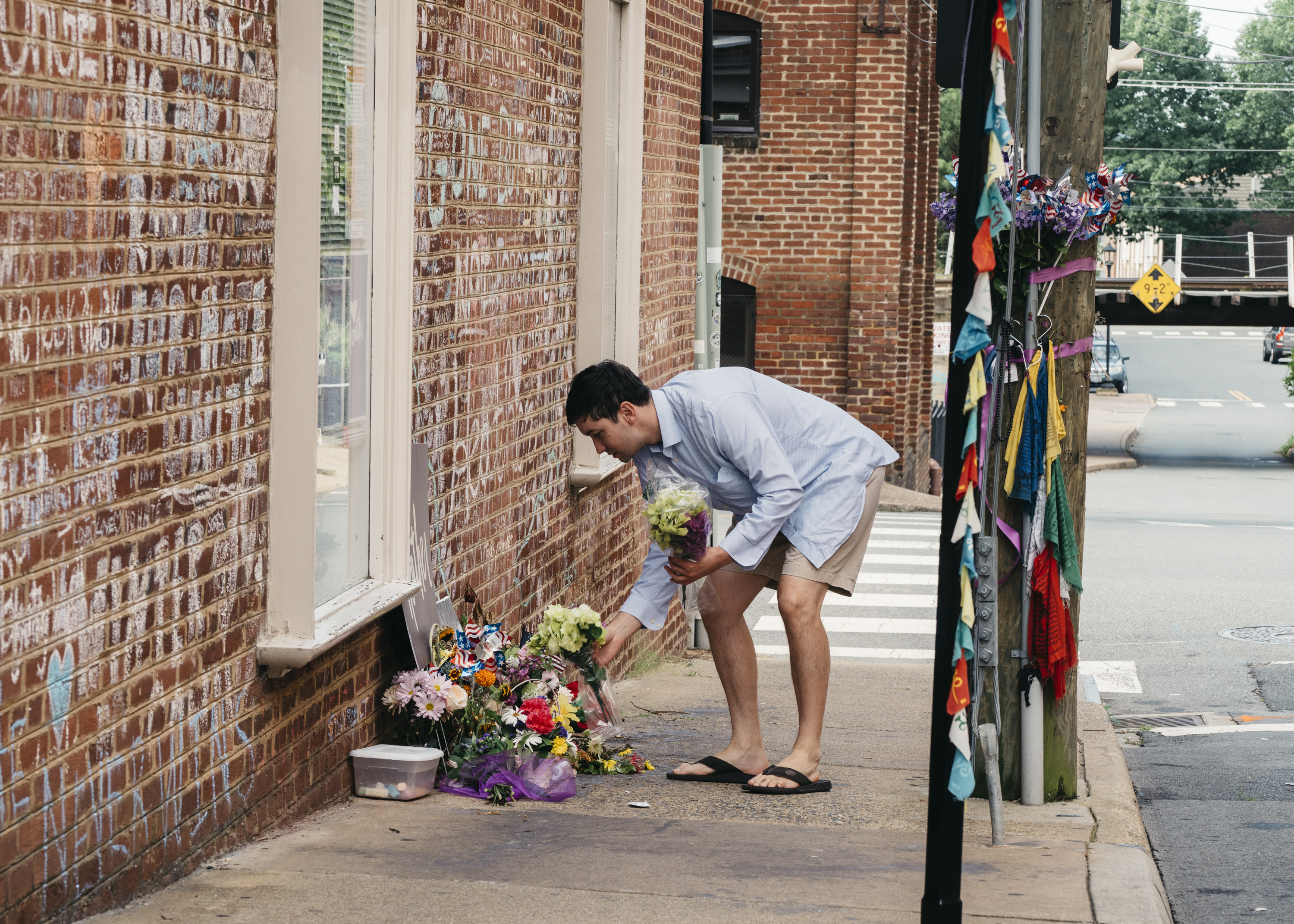 Peter Reijmers, 29, of Charlottesville, lays flowers at a memorial on 4th Street SE where Heather Heyer was killed last August. (Justin T. Gellerson for NPR)