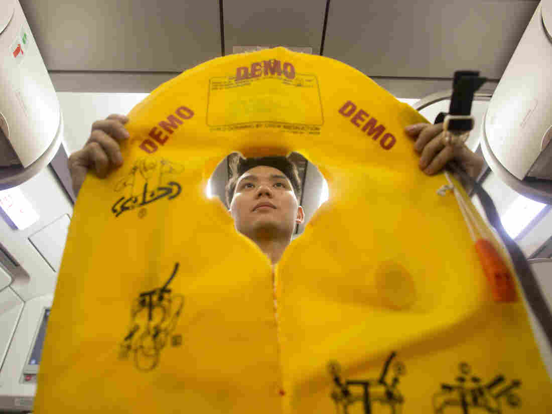 A flight attendant holds an inflatable life vest during a safety presentation on board a VietJet Air aircraft.
