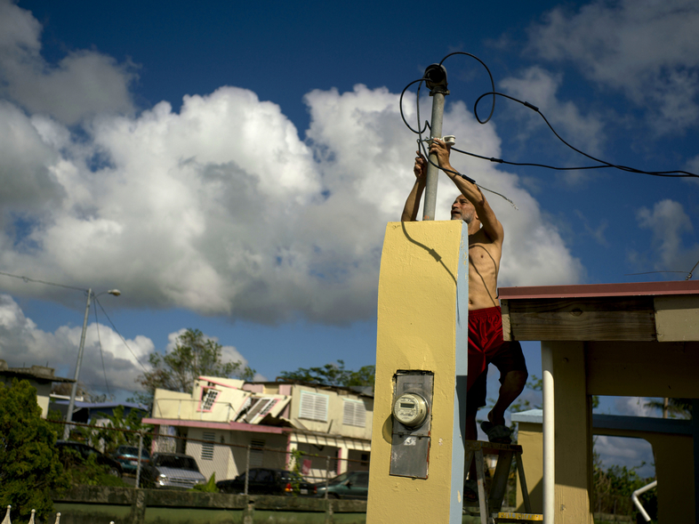 In October 2017, a resident tries to connect electrical lines downed by Hurricane Maria in Toa Baja. Puerto Rican officials say electricity has returned to all residents without it after the hurricane. (Ramon Espinosa/AP)