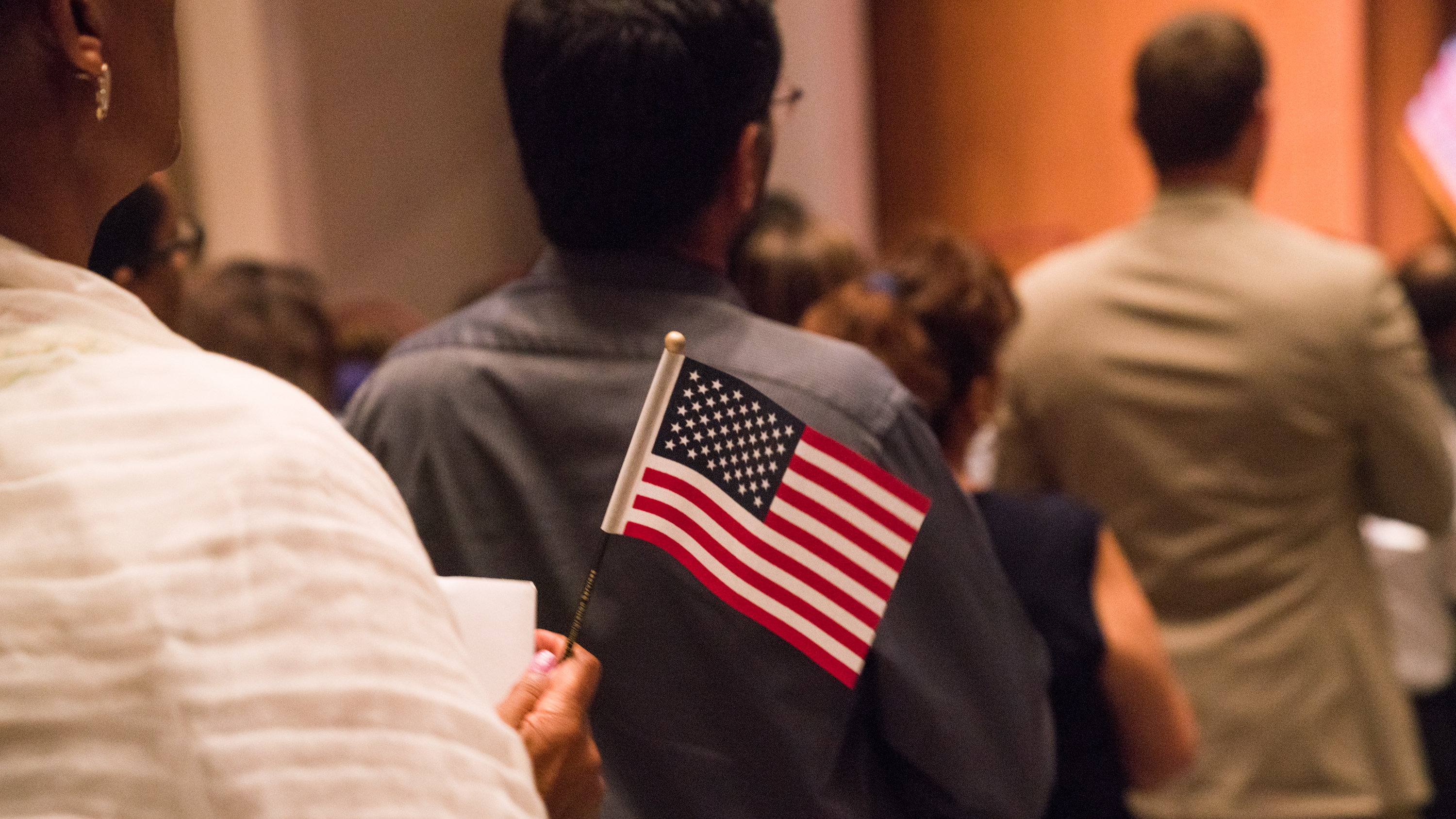 Newly sworn-in U.S. citizens gathered for a naturalization ceremony at the Rachel M. Schlesinger Concert Hall and Arts Center in Alexandria, Va., in August. (NPR)