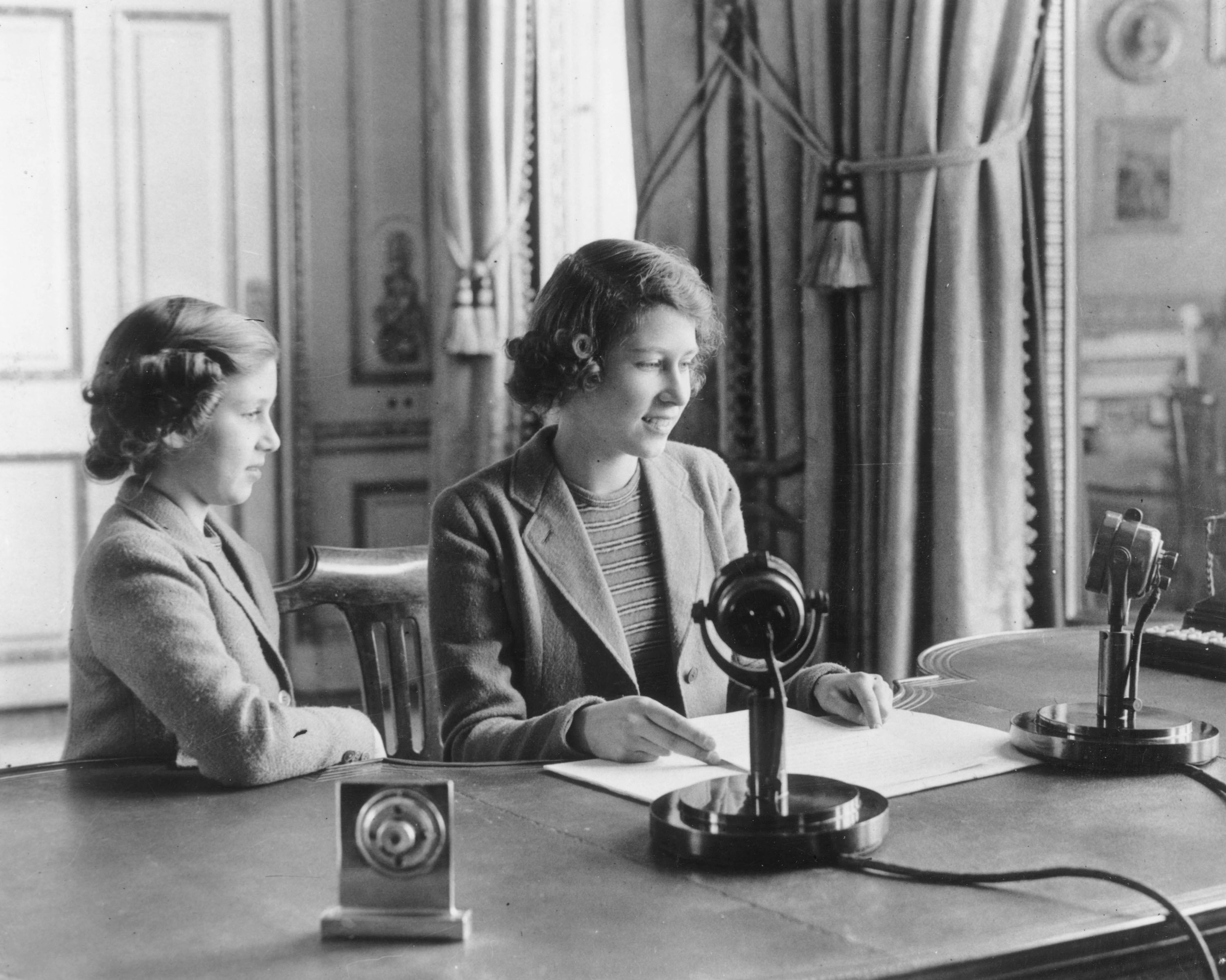 Princess Margaret watches her older sister Princess Elizabeth make her first broadcast on Oct. 12, 1940 in London. (Getty Images)