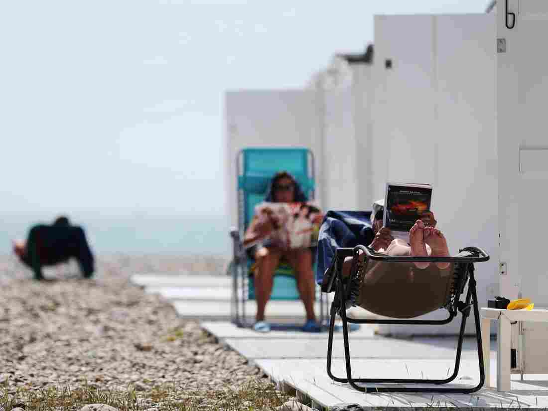 People sit reading on the beach on a sunny day in Le Havre, northwestern France, on May 27, 2016. / AFP / CHARLY TRIBALLEAU (Photo credit should read CHARLY TRIBALLEAU/AFP/Getty Images)