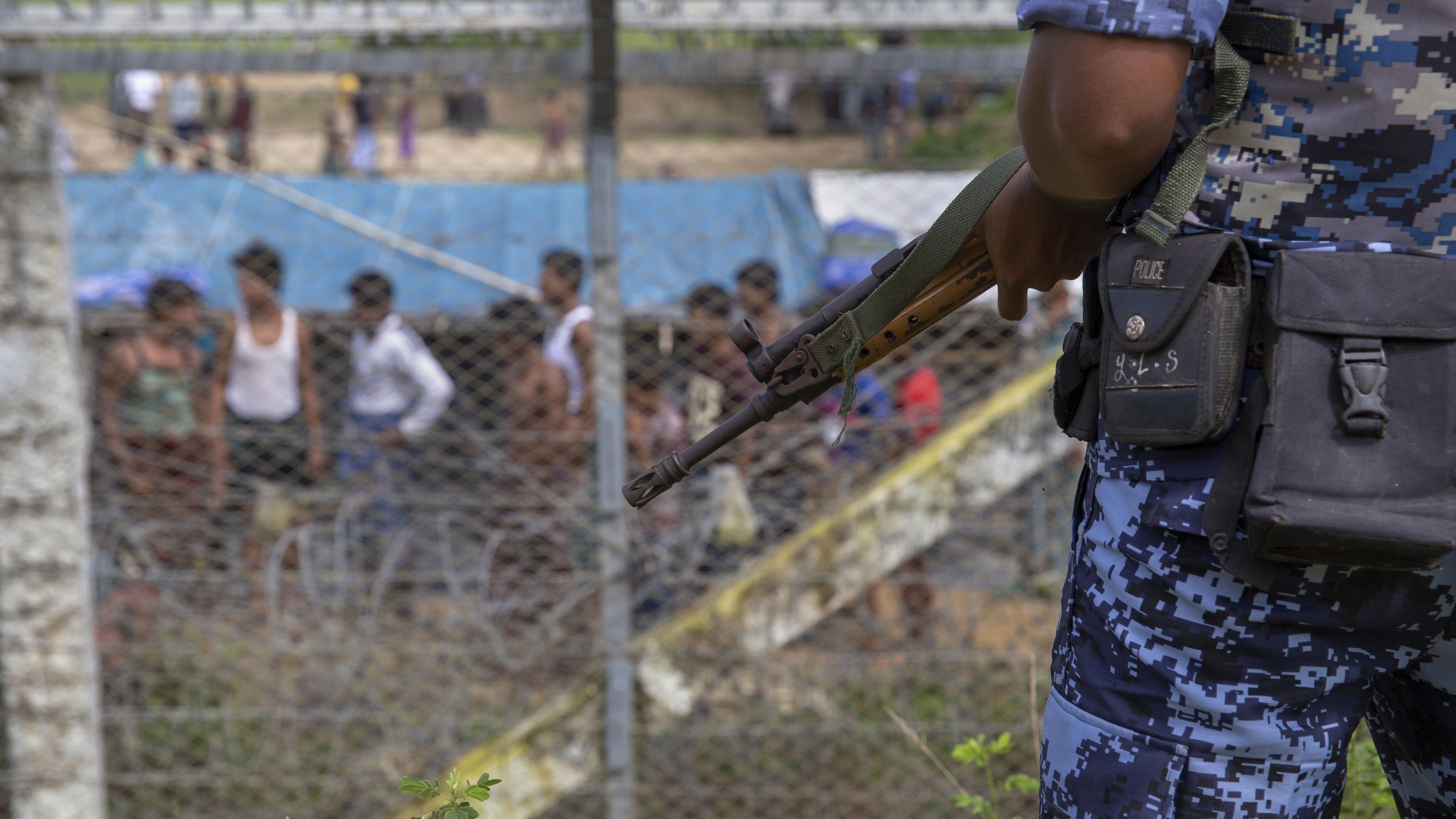 Myanmar border guard police patrol the fence in the &quot;no man's land&quot; zone between Myanmar and Bangladesh, as seen from Maungdaw, Rakhine state, during a government-organized visit for journalists on Aug. 24. A new U.N. report finds that Myanmar's military and other groups, including the border police, committed atrocities. The report urges the prosecution of military leaders for genocide. (AFP/Getty Images)