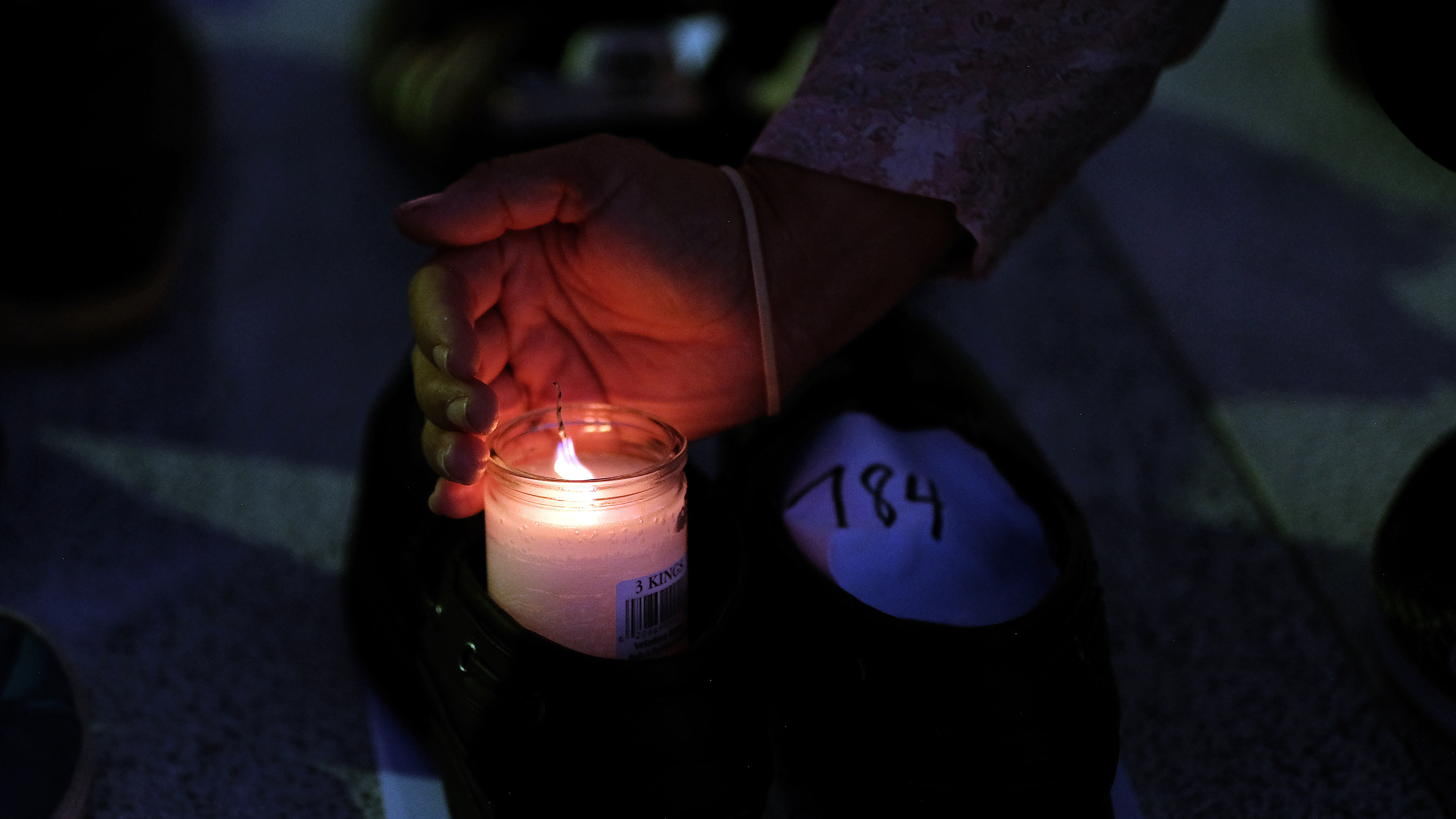 A woman lights a candle inside a pair of shoes that were among hundreds displayed in memory of those killed by Hurricane Maria in front of the Puerto Rican Capitol, in San Juan in June. (AFP/Getty Images)
