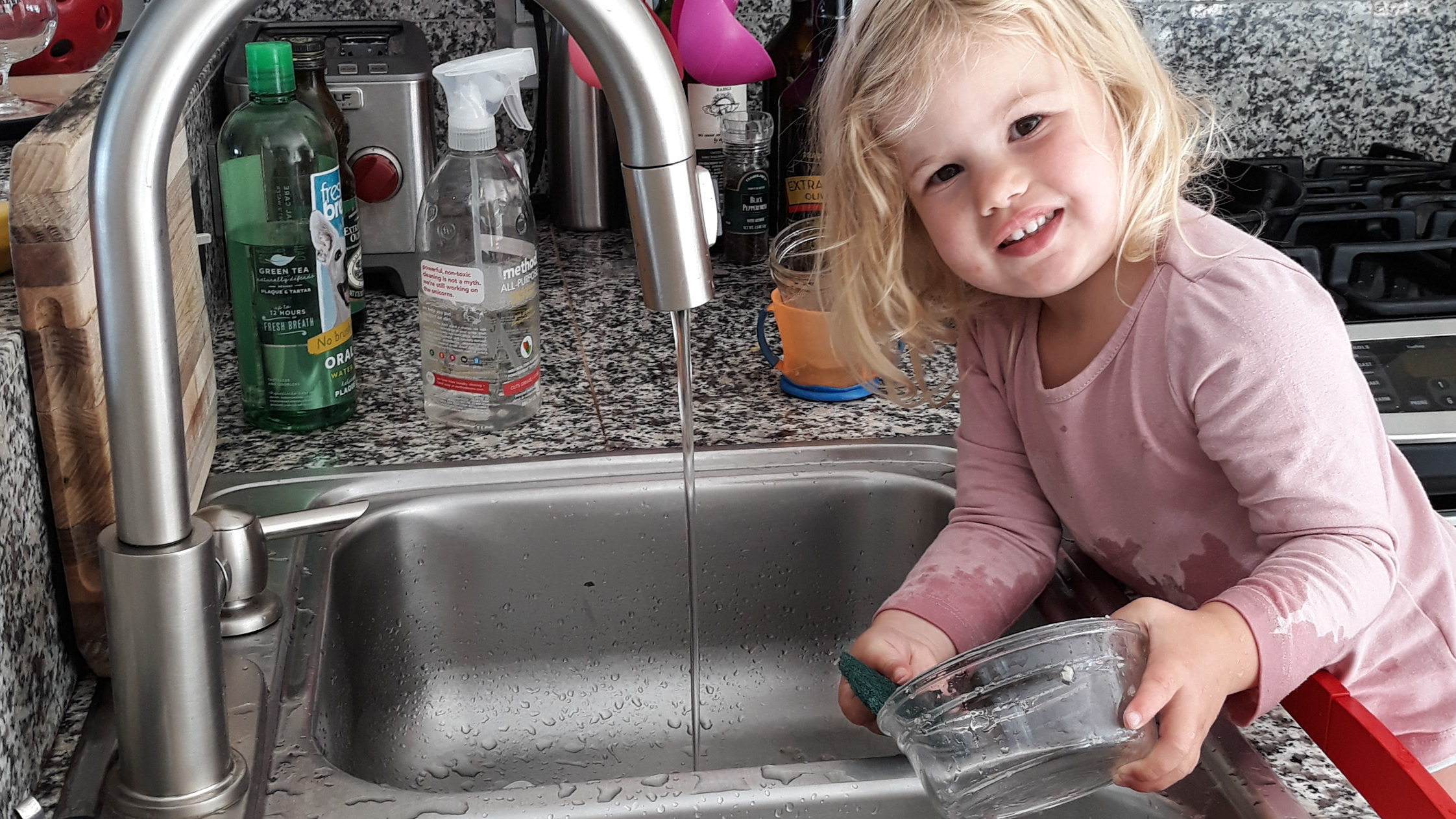 Rosy does dishes. Getting the 2-year-old involved in chores did lead to the kitchen being flooded and dishes being broken. But now she is still eager to help.