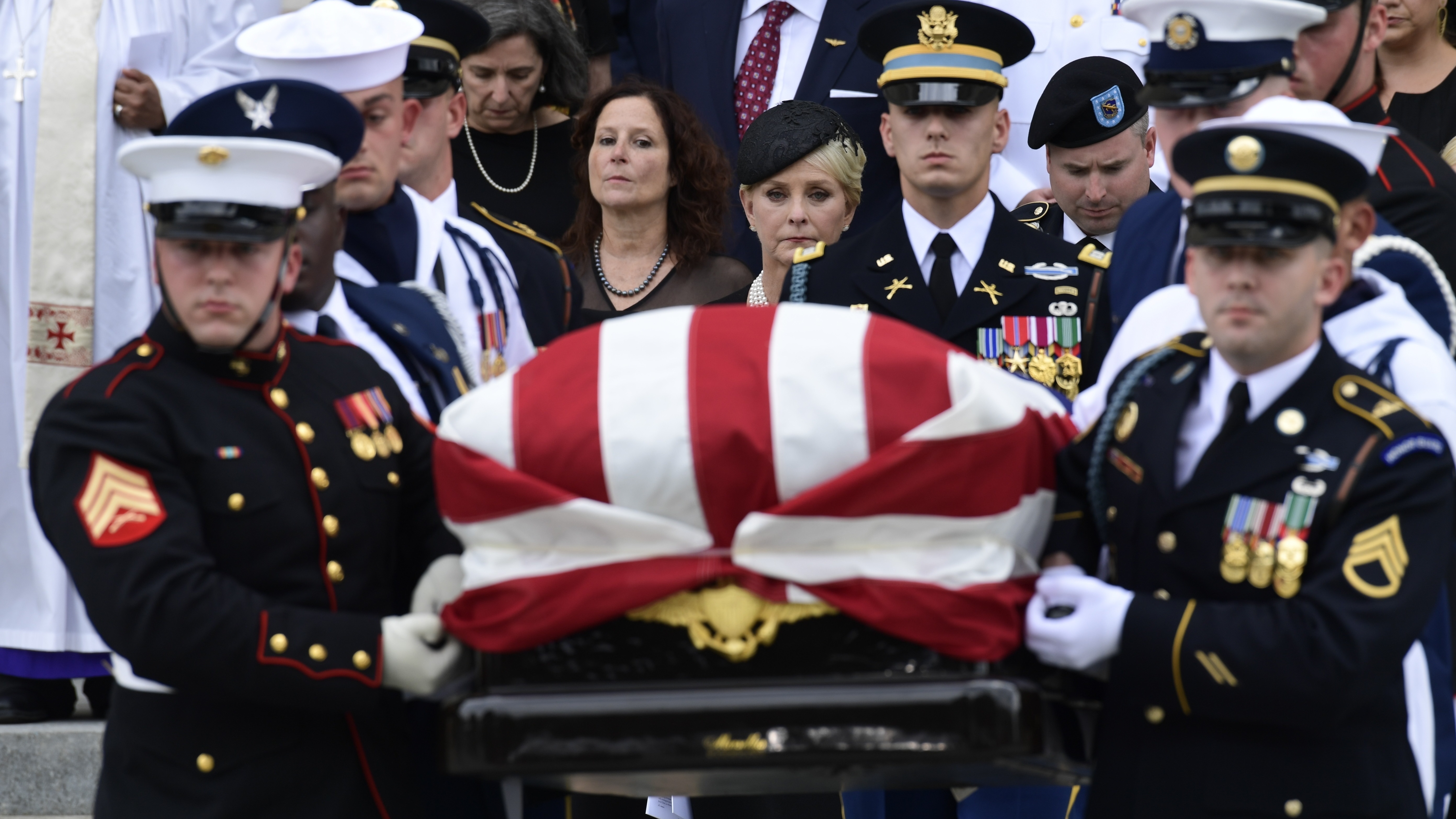 The casket of Sen. John McCain, R-Ariz., is carried out of the Washington National Cathedral in Washington, Saturday, after a memorial service, as Cindy McCain is escorted by her son Jimmy McCain and other family members.