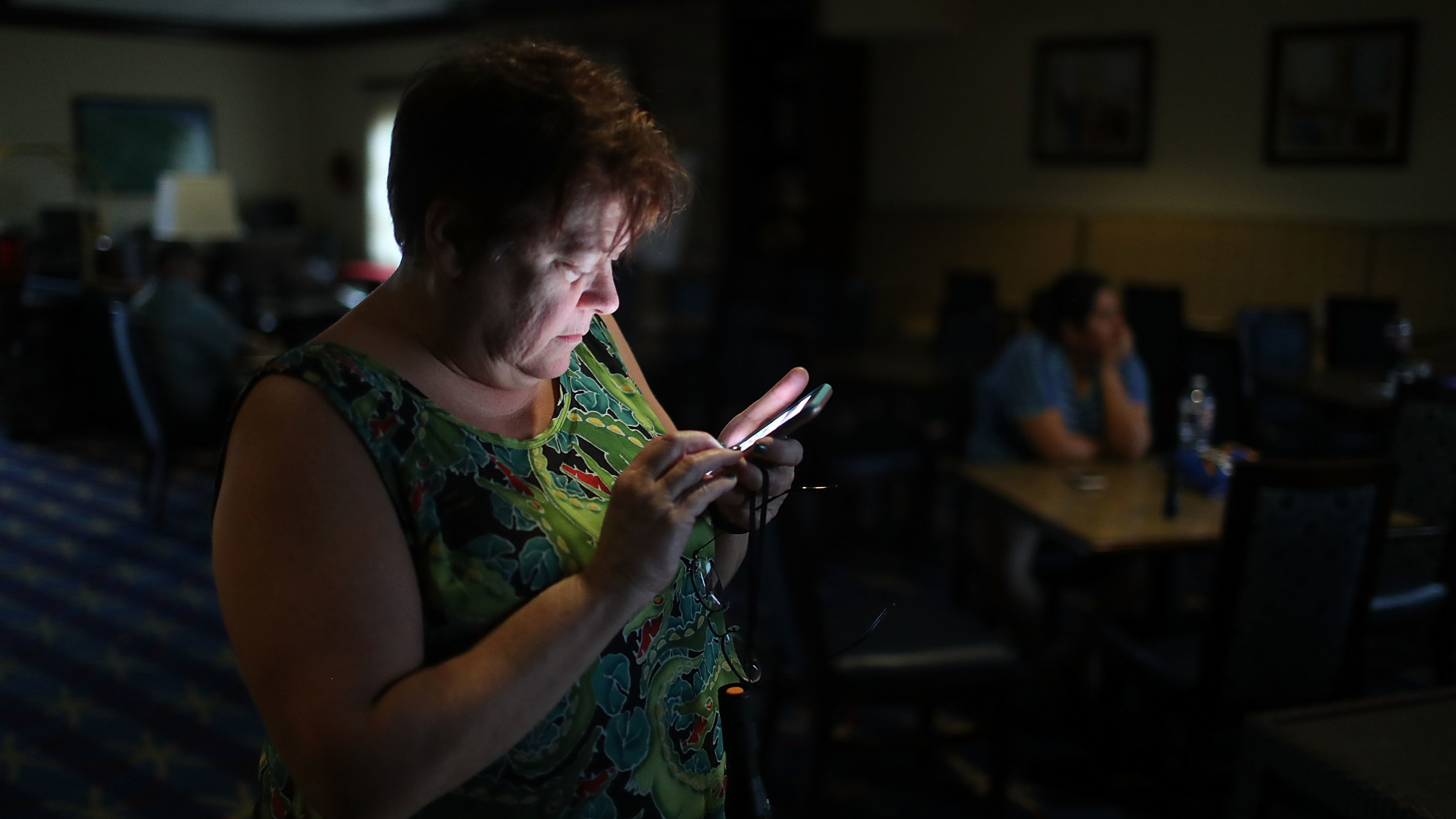 Amy Currin watches the weather news on her cell phone after the power went out at the hotel where she was taking shelter from Hurricane Harvey last August. (Getty Images)