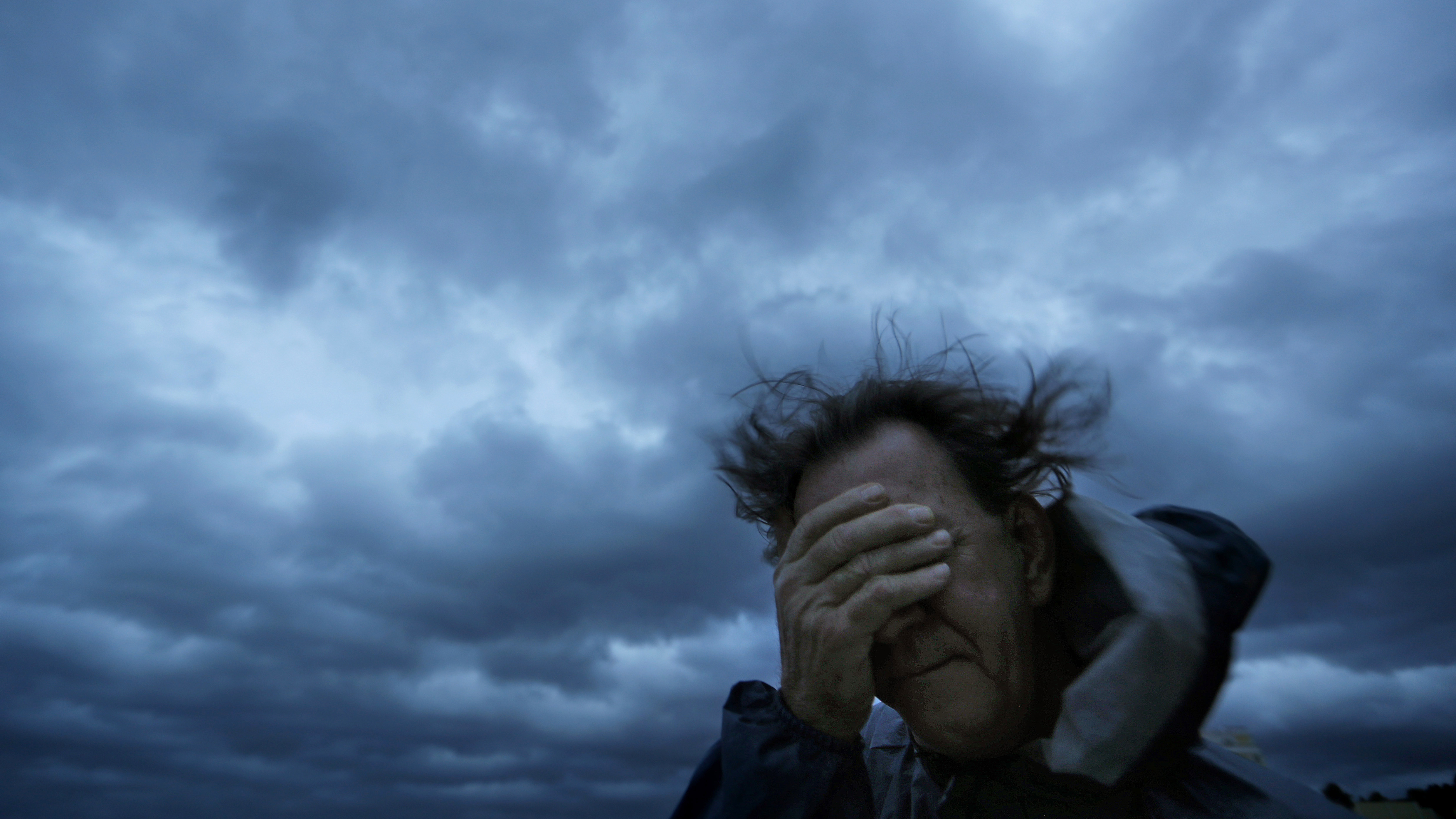 Russ Lewis covers his eyes from a gust of wind and a blast of sand as Hurricane Florence approaches Myrtle Beach, S.C. Even as mandatory evacuation orders were issued, many chose to stay.