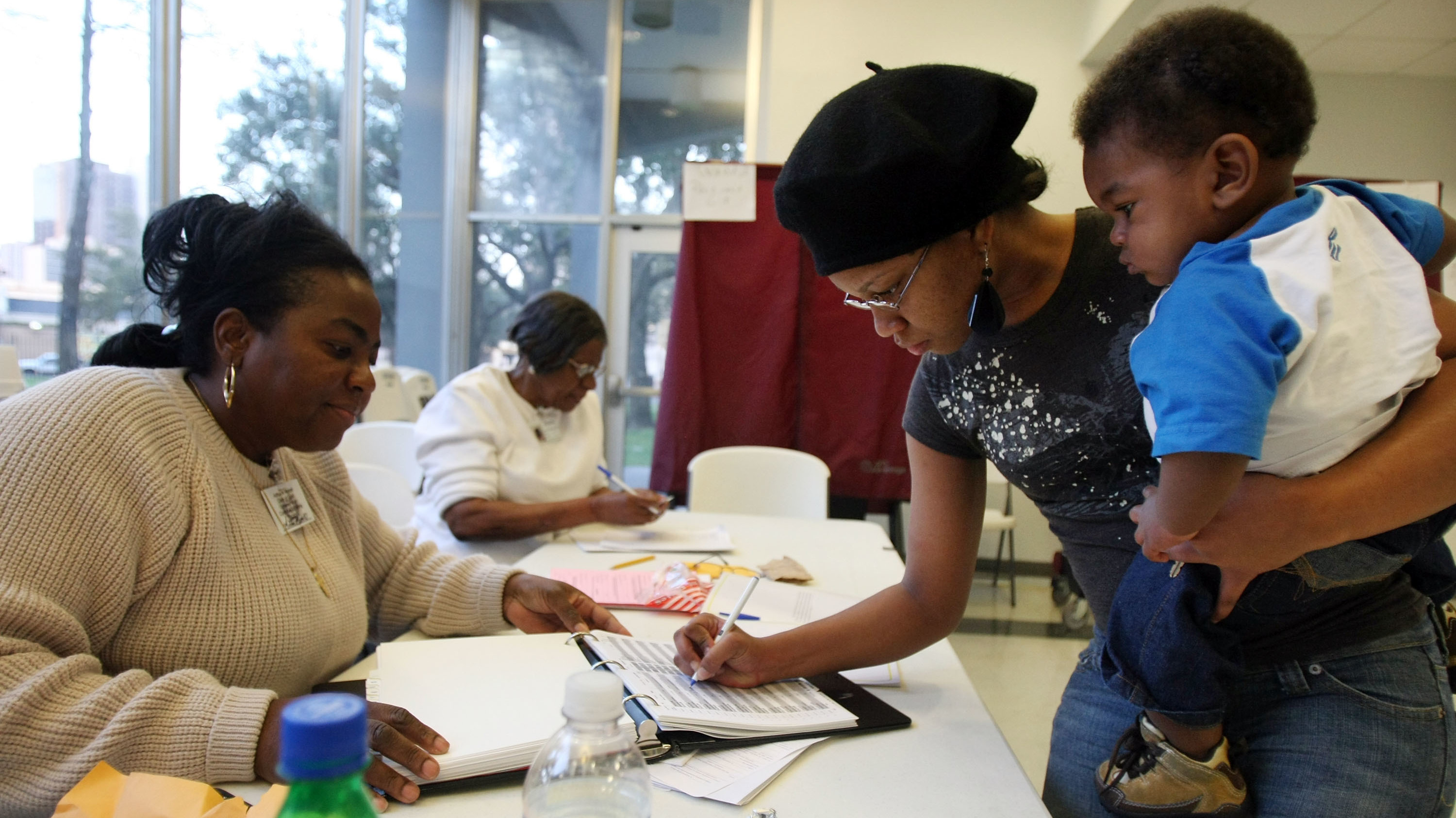 Charnisha Thomas signs in during the Louisiana presidential primary in 2008. In a new poll released Monday, African-American voters say they wait in longer lines and travel farther to get to polling places than white voters. (Getty Images)