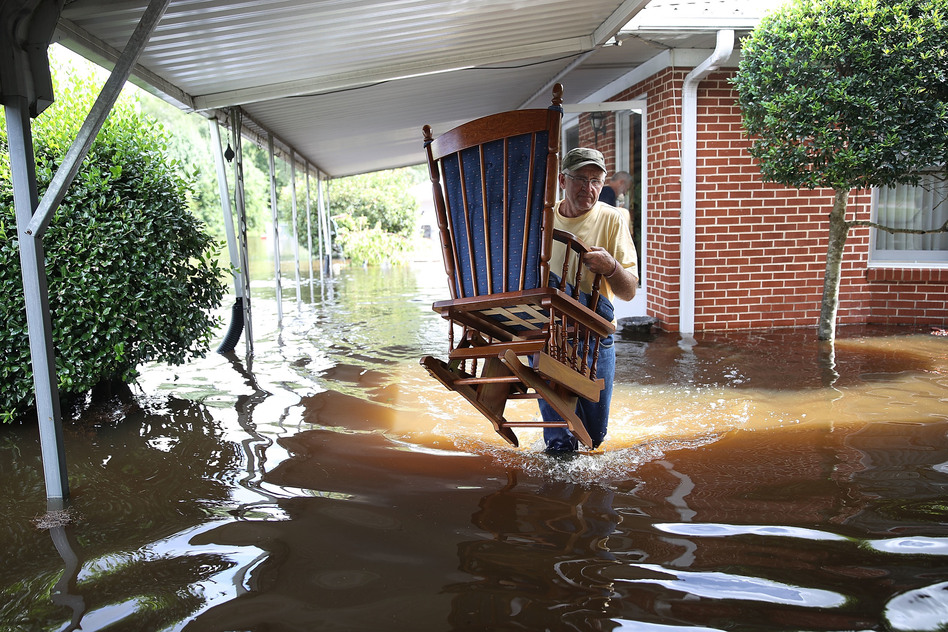 Bob Richling carries items from the home of Iris Darden as floodwater from the Little River starts to seep into her home Monday in Spring Lake, N.C. (Joe Raedle/Getty Images)