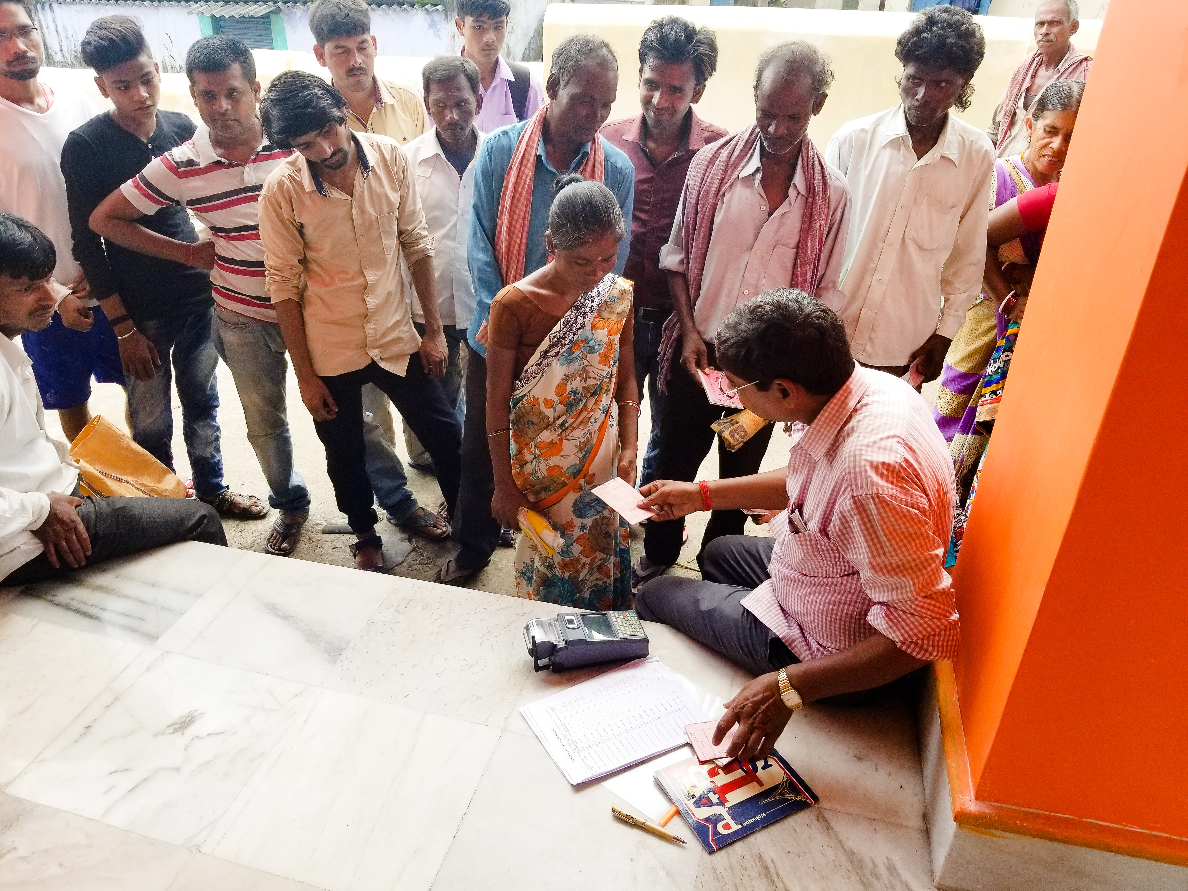 Ashok Kumar (foreground) works at a food ration distribution shop in Jharkhand. He uses a small machine to scan people's fingerprints and check them against Aadhaar ID numbers. (NPR)