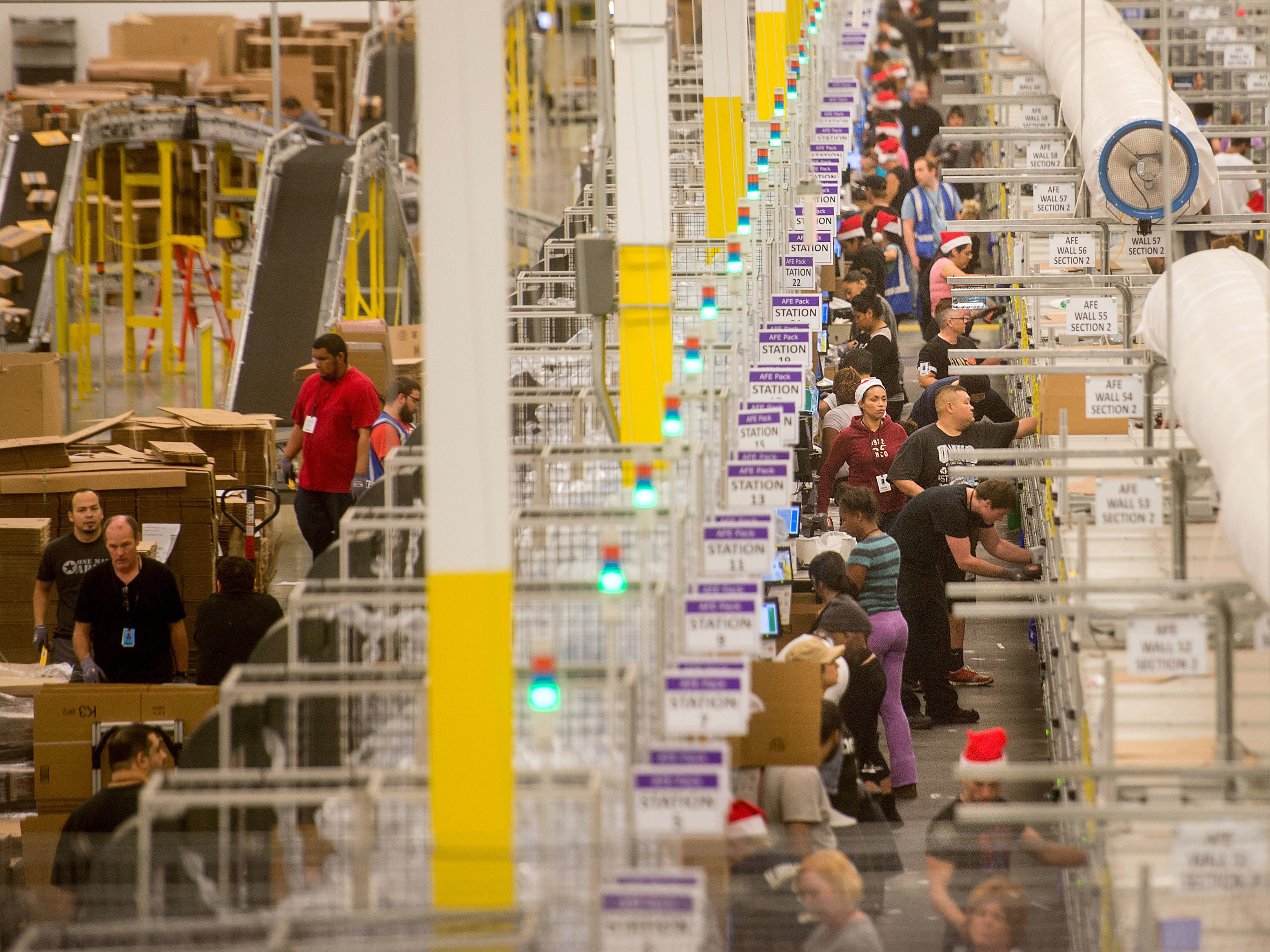 Amazon says it will pay all its U.S. workers at least $15 an hour. Here, workers prepare shipments at an Amazon Fulfillment Center in California during the early Christmas rush in 2014. (Reuters)