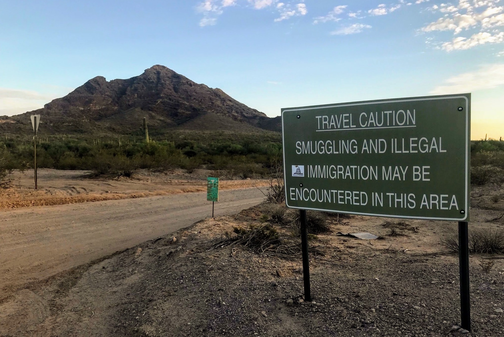 A sign outside Ajo, Ariz., warns hikers to keep an eye out for people who have unlawfully crossed the nearby border with Mexico. No More Deaths and other humanitarian groups use a private residence they call &quot;the barn&quot; on the outskirts of the small town as a base of operations. (NPR)