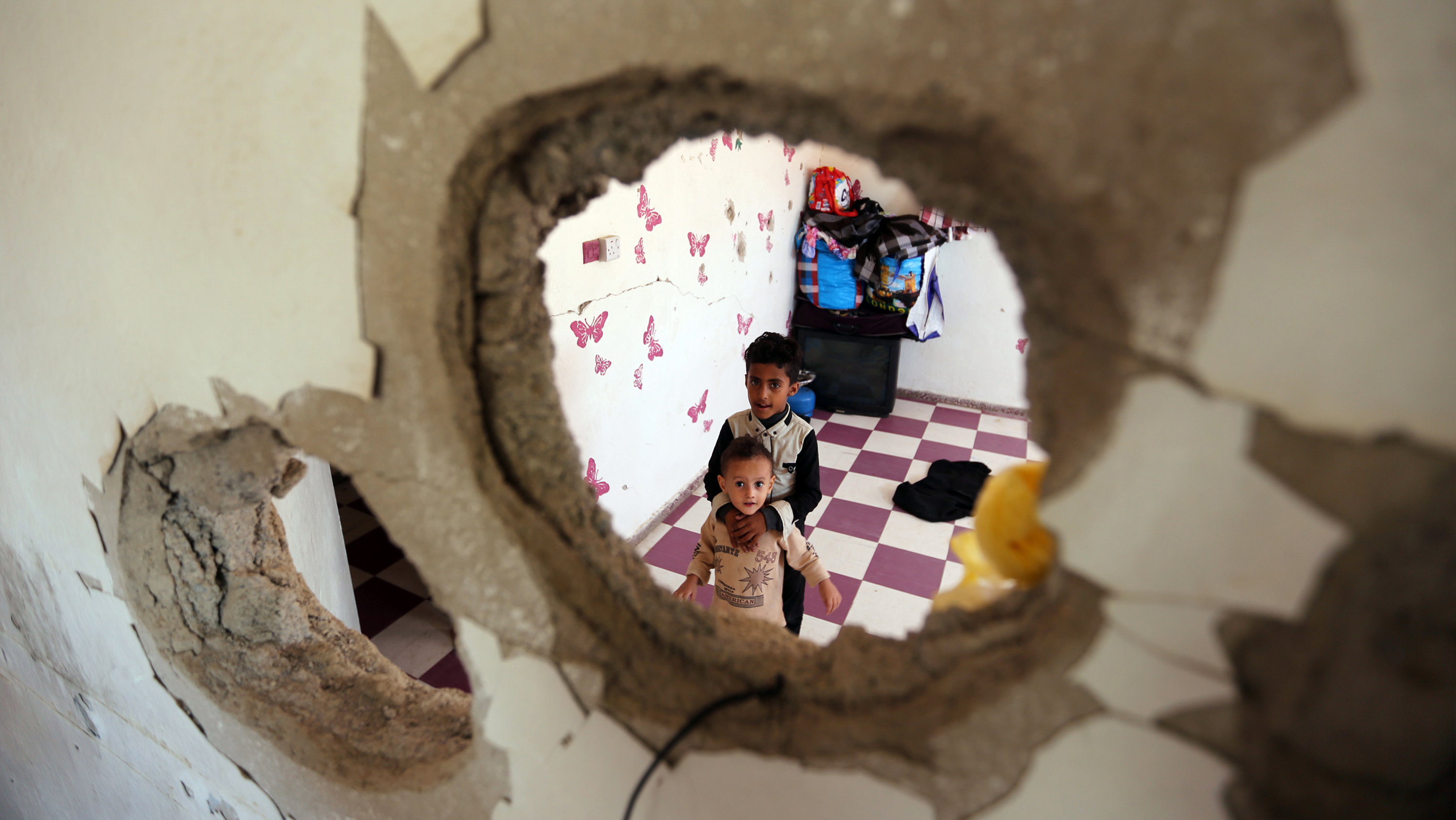 Displaced Yemeni children stare through a hole in the wall of a half-destroyed house in Taez, where they have been staying with several families since violence drove them from their homes in Hodeidah earlier this year. (AFP/Getty Images)