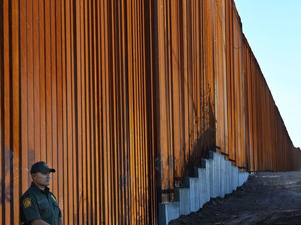 A border protection officer stands next to a recently upgraded section of fencing at the U.S.-Mexico border in Calexico, Calif., on Friday. The Pentagon says it will send 5,000 U.S. troops to the border.