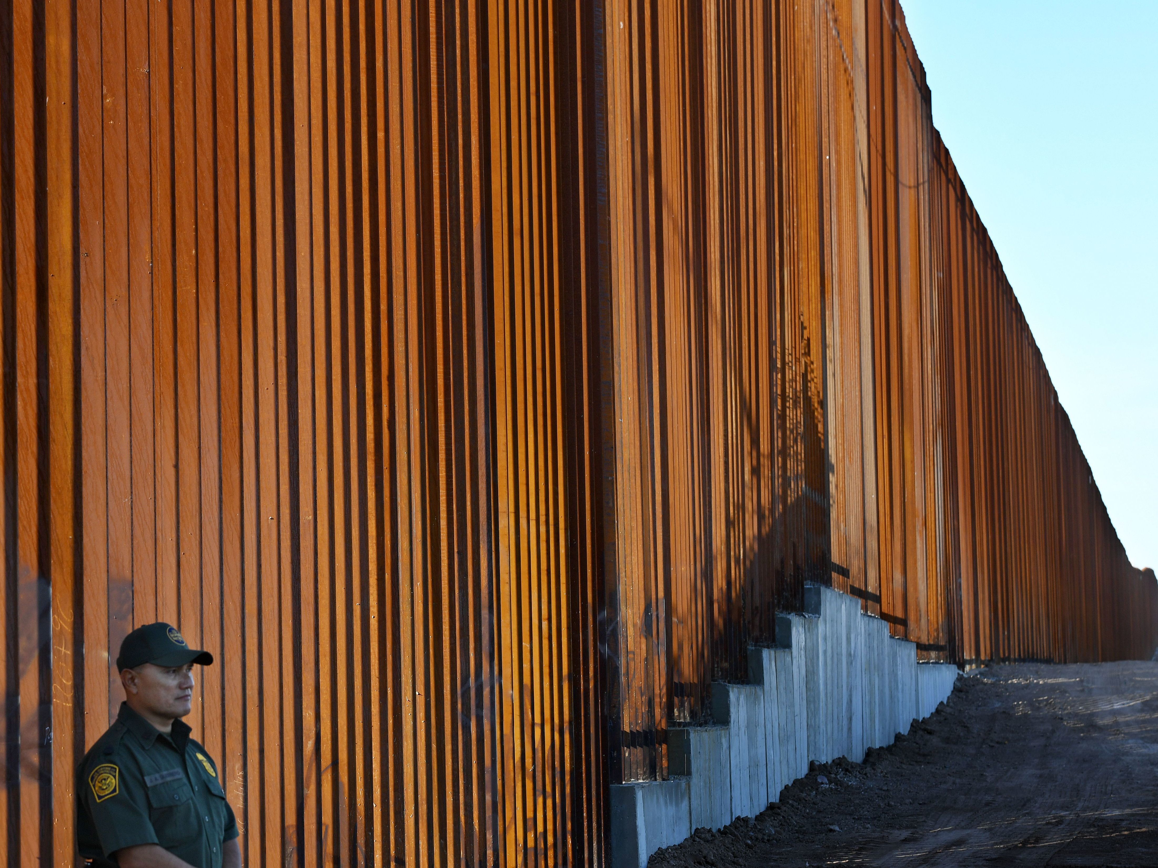 A border protection officer stands next to a recently upgraded section of fencing at the U.S.-Mexico border in Calexico, Calif., on Friday. The Pentagon says it will send 5,000 U.S. troops to the border. (AFP/Getty Images)