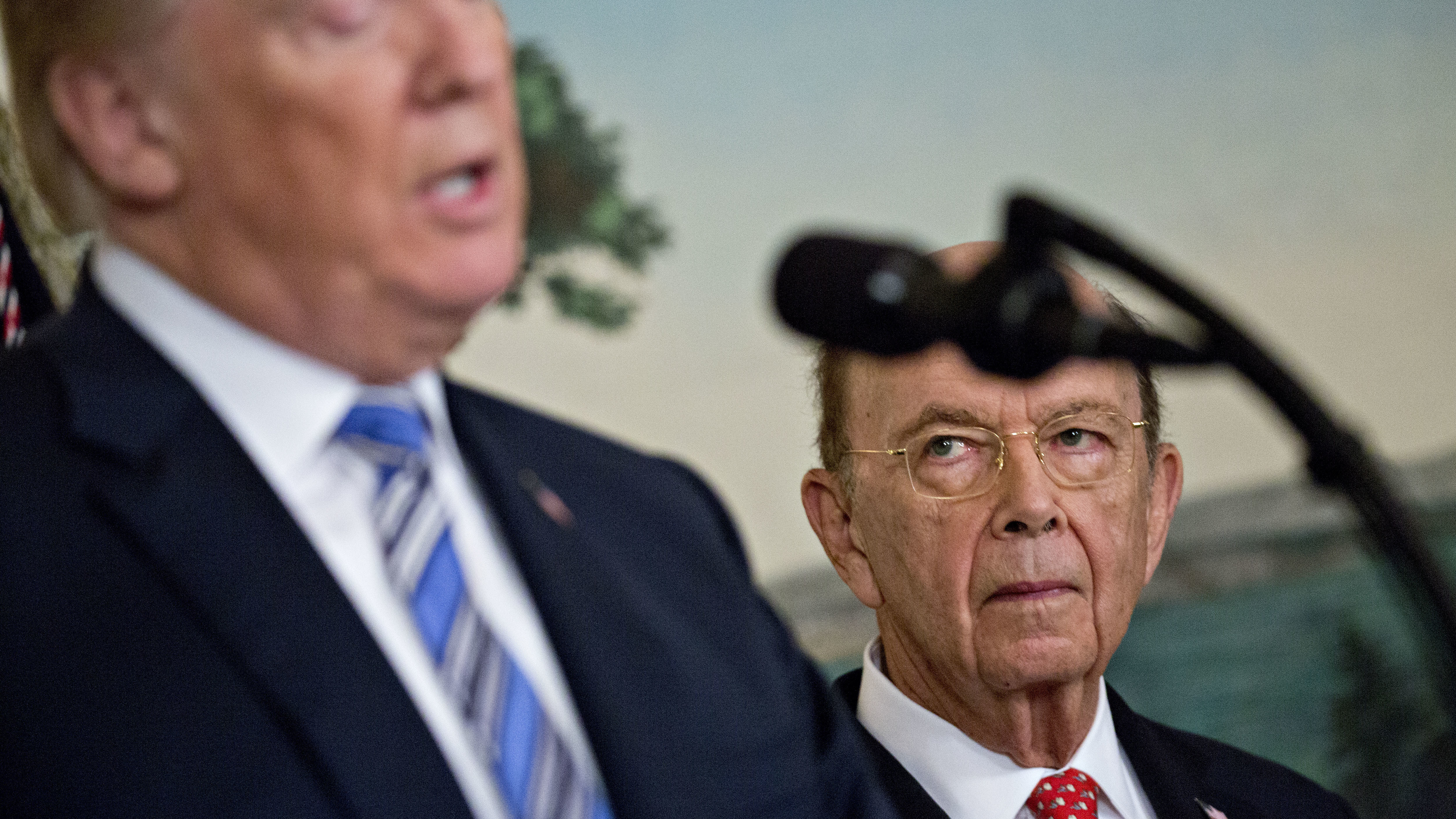 Commerce Secretary Wilbur Ross listens to President Trump at the White House in March. Ross' decision to add a question about U.S. citizenship status to the 2020 census sparked six lawsuits from dozens of states, cities and other groups that want the question removed. (Bloomberg via Getty Images)