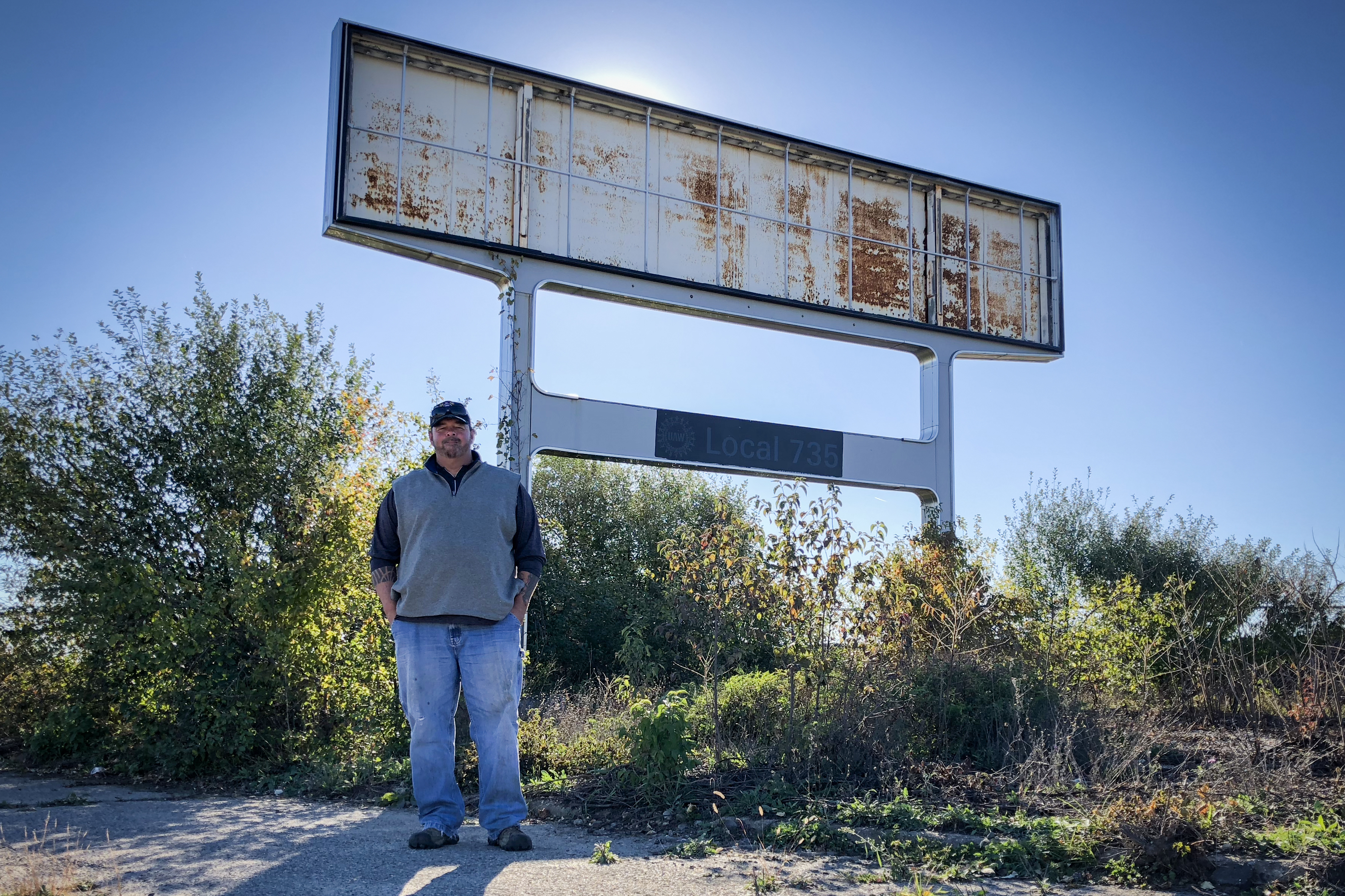 Don Skidmore stands in front of a sign for United Auto Workers Local 735, the union chapter he represented as president when he was a General Motors employee. (NPR)