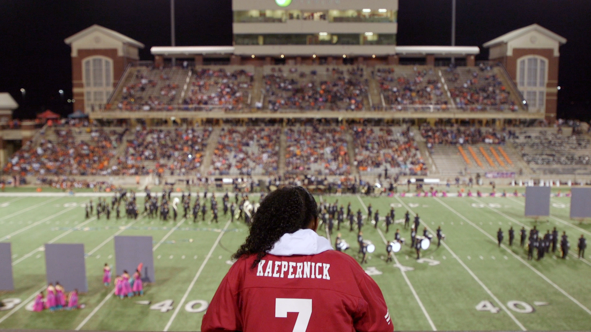 Wearing a Colin Kaepernick jersey, India Landry stands high in a high-school football stadium. (NPR)