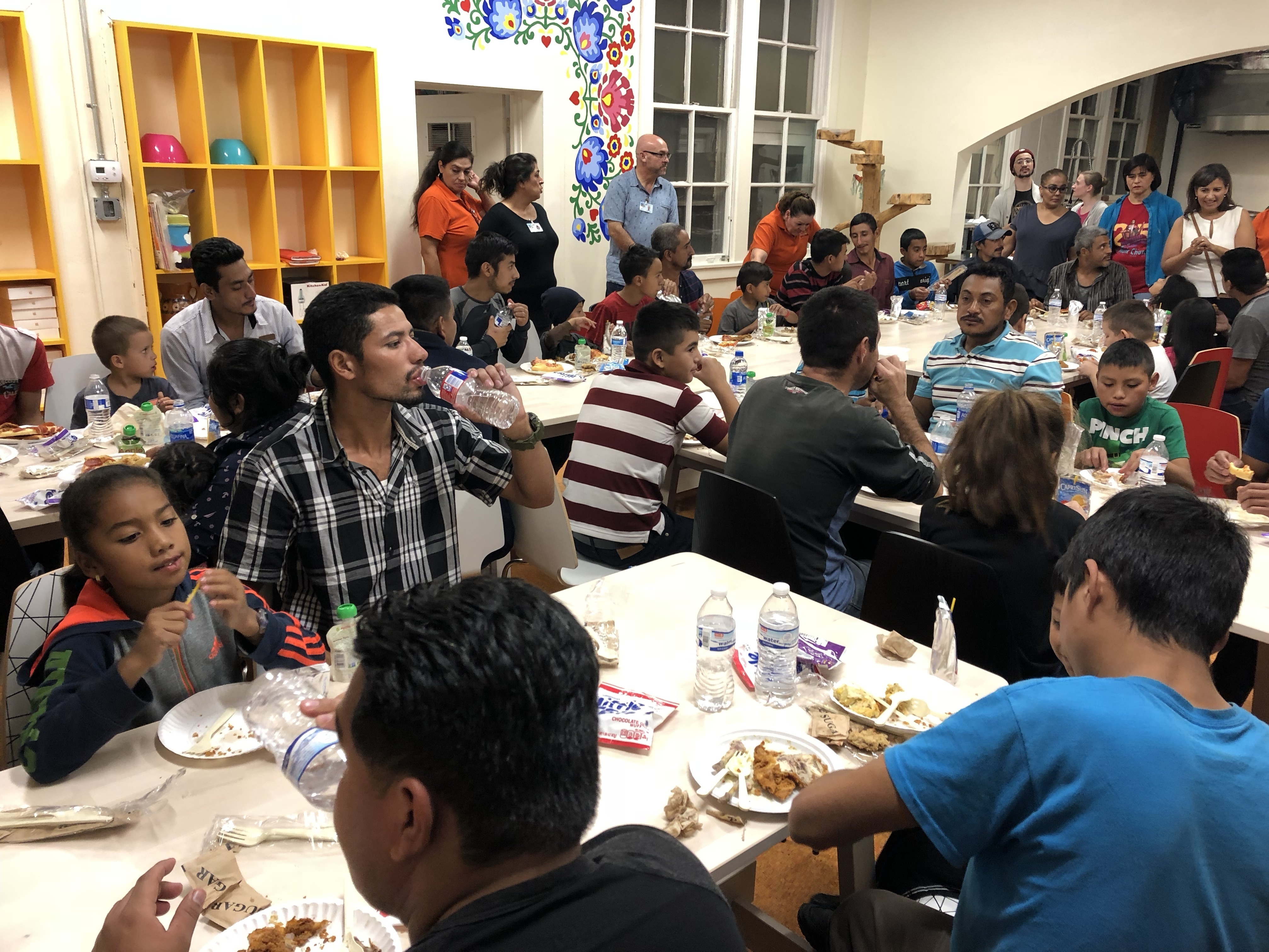 Families eat dinner at Holy Family Church in El Paso. Immigration officials have been releasing hundreds of asylum-seeking migrants into border communities. Churches and shelters are standing by to help. (KRWG)