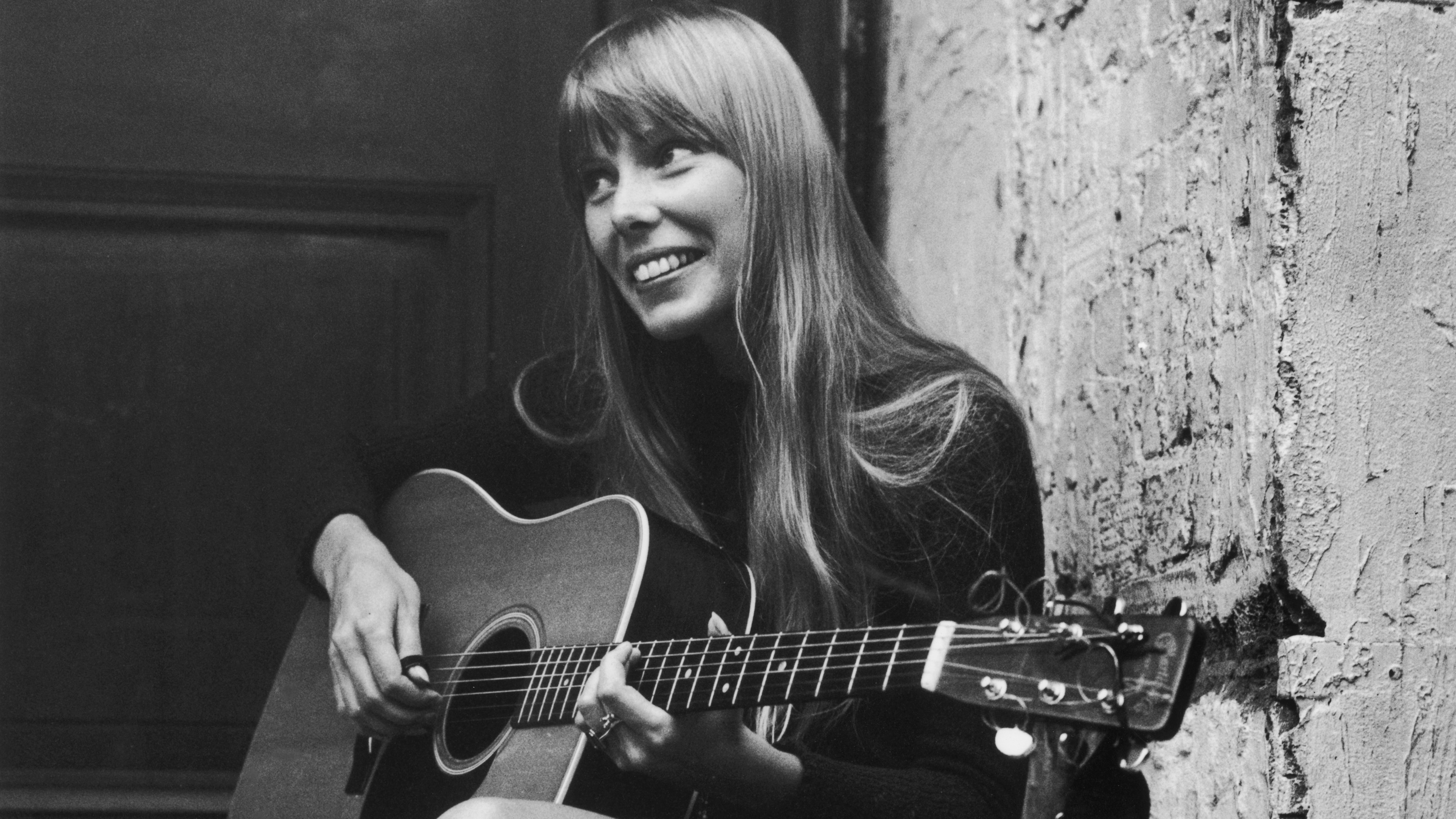 Joni Mitchell strums her guitar outside The Revolution club in London in 1968. (Getty Images)
