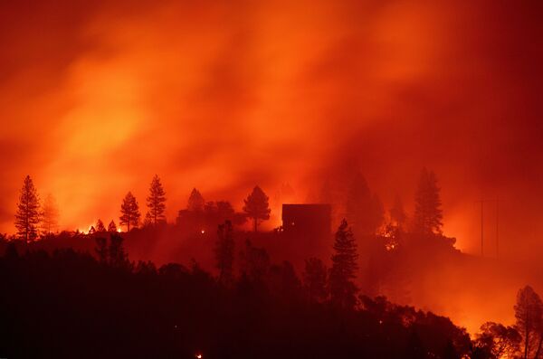 Flames from the Camp Fire burn near a home atop a ridge near Big Bend.