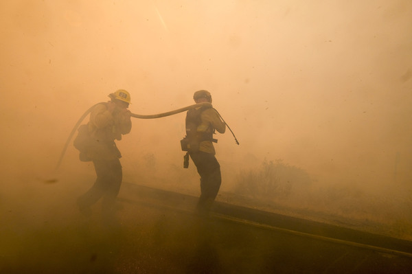 Firefighters battle a fire along the Ronald Reagan Freeway in Simi Valley, Calif.