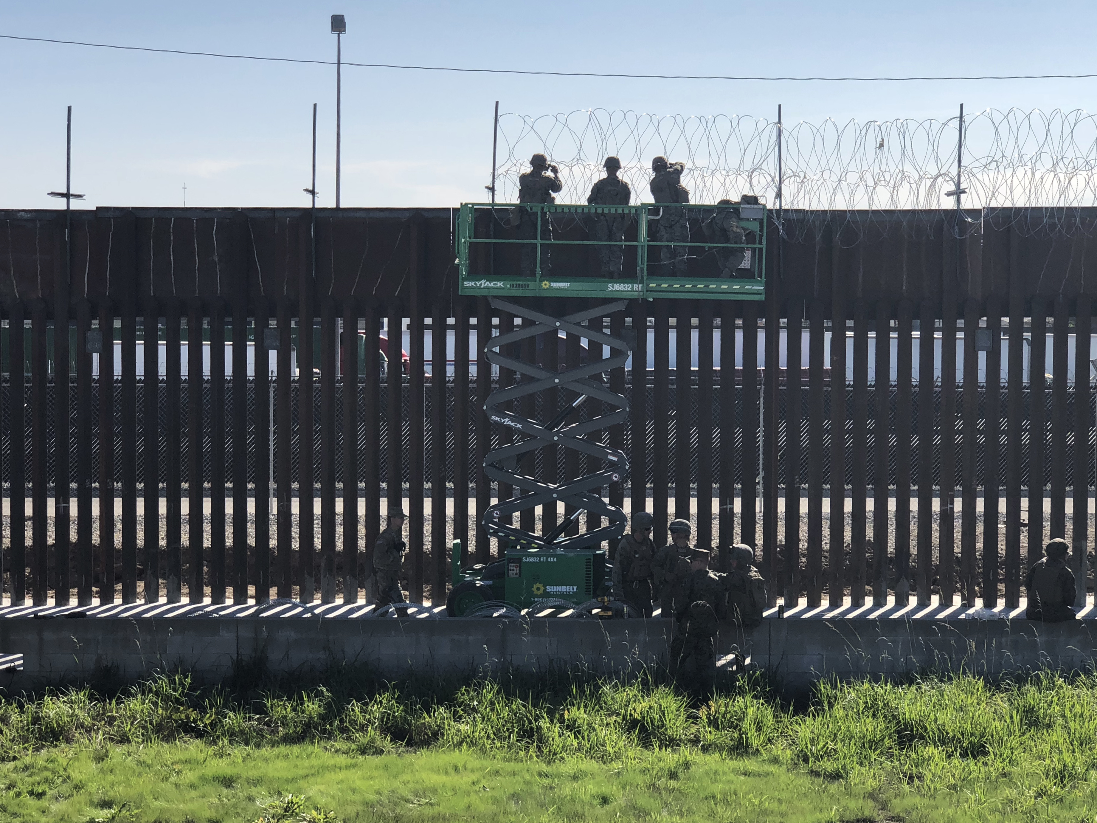 Marines install concertina wire on top of a border fence at the Otay Mesa port-of-entry. The facility, east of San Diego, is primarily used for commercial cargo passing back and forth between the U.S. and Mexico. (KPBS)